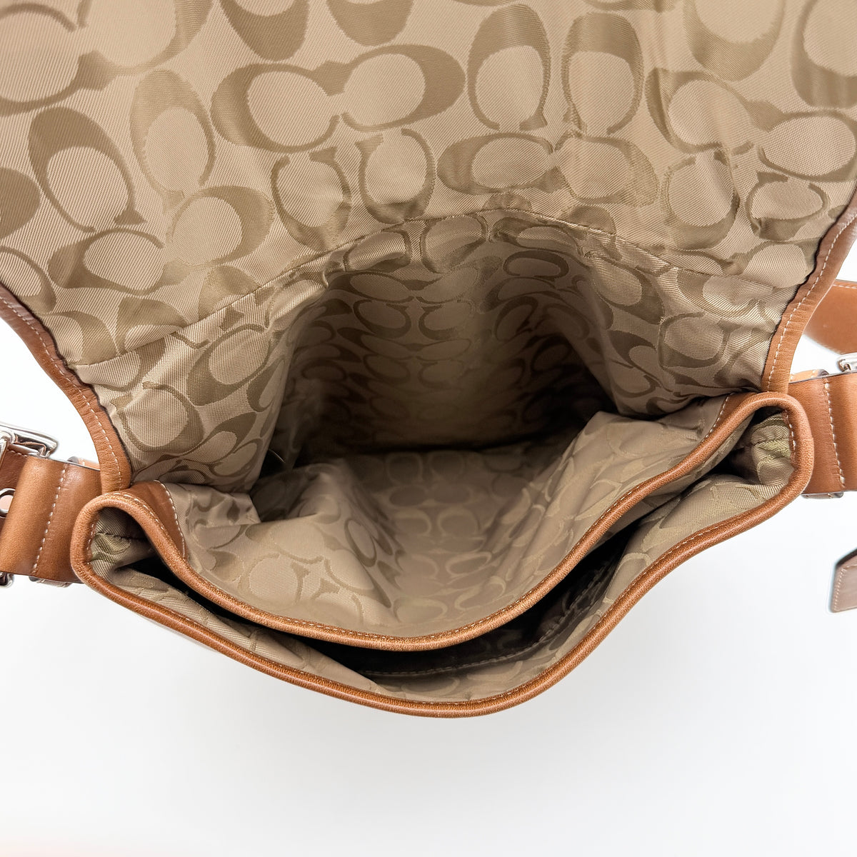 Coach Soho Buckle Flap Crossbody Bag in brown leather with buckle flap and adjustable strap, displayed on white background.