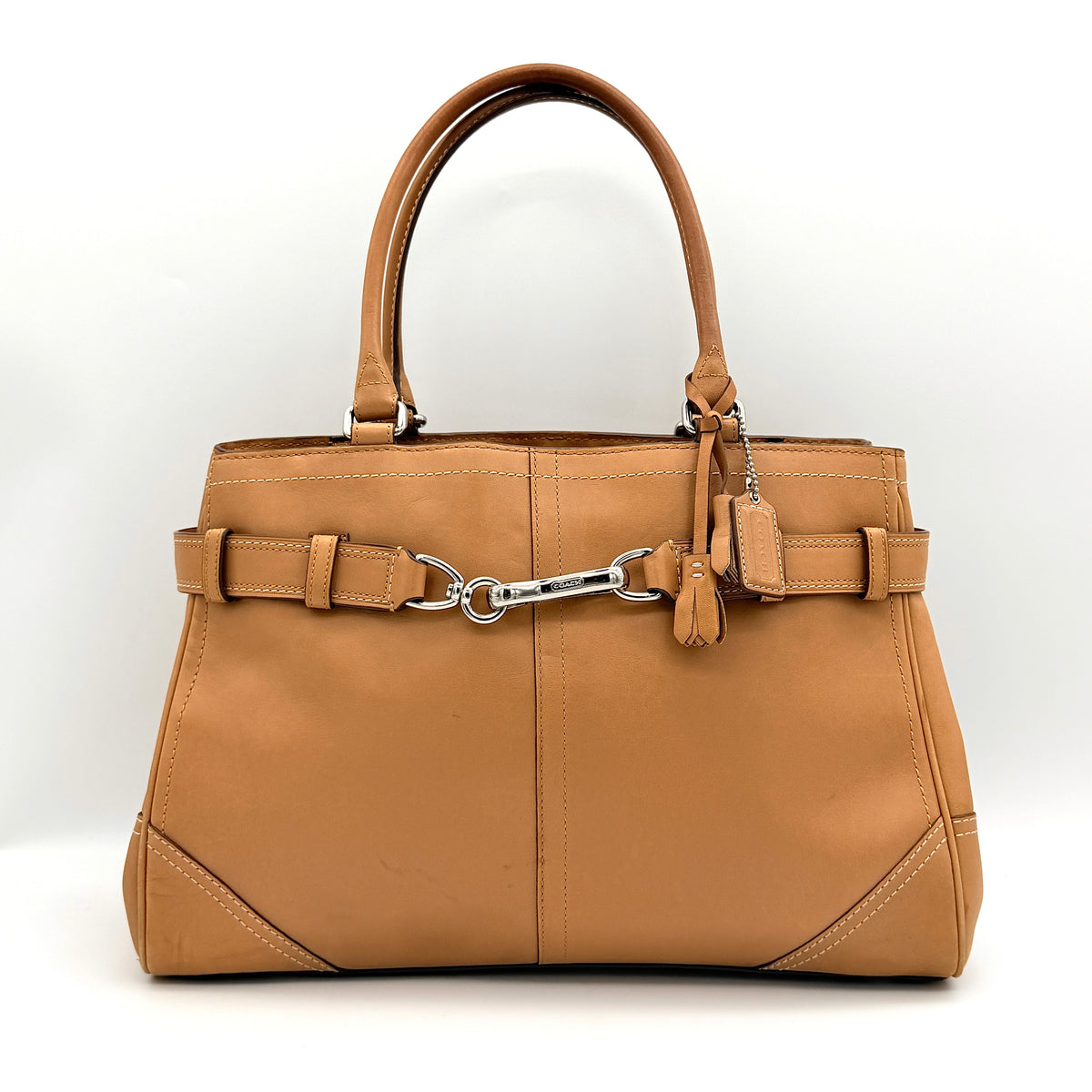 Coach Hampton Carryall in caramel brown leather with silver hardware and double handles, photographed against a white backdrop.