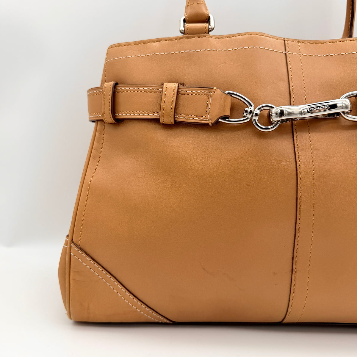 Coach Hampton Carryall in caramel brown leather with silver hardware and double handles, photographed against a white backdrop.