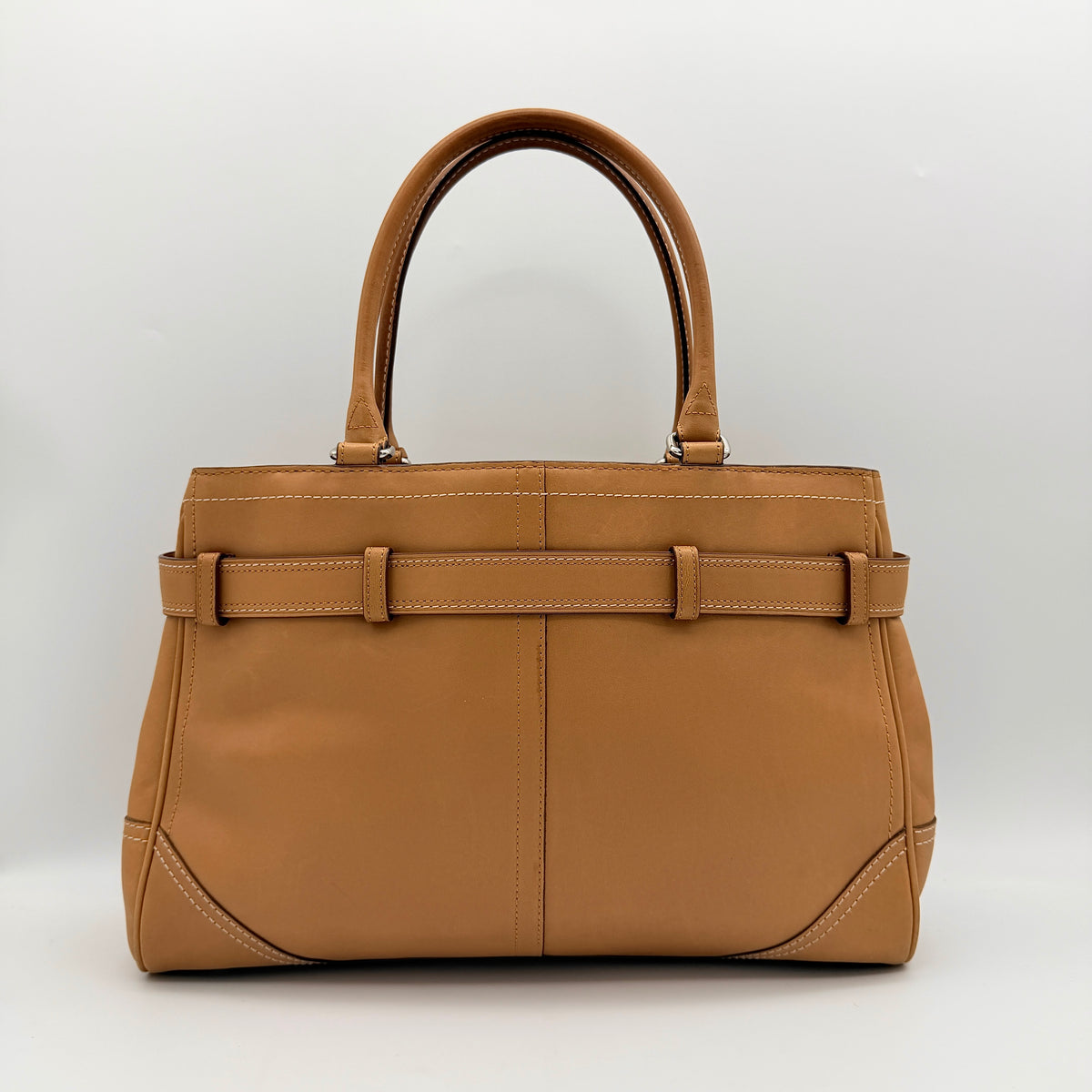 Coach Hampton Carryall in caramel brown leather with silver hardware and double handles, photographed against a white backdrop.