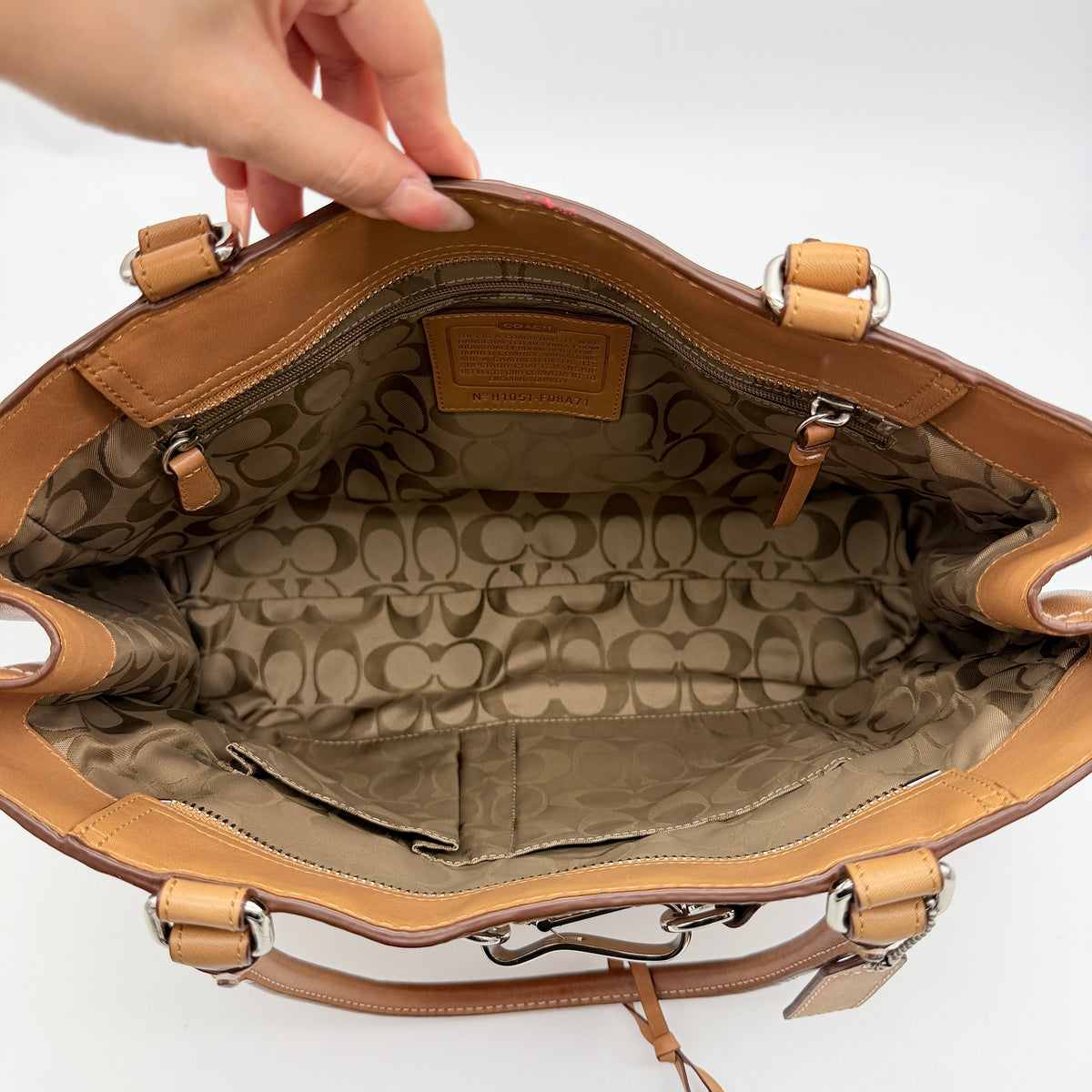 Coach Hampton Carryall in caramel brown leather with silver hardware and double handles, photographed against a white backdrop.