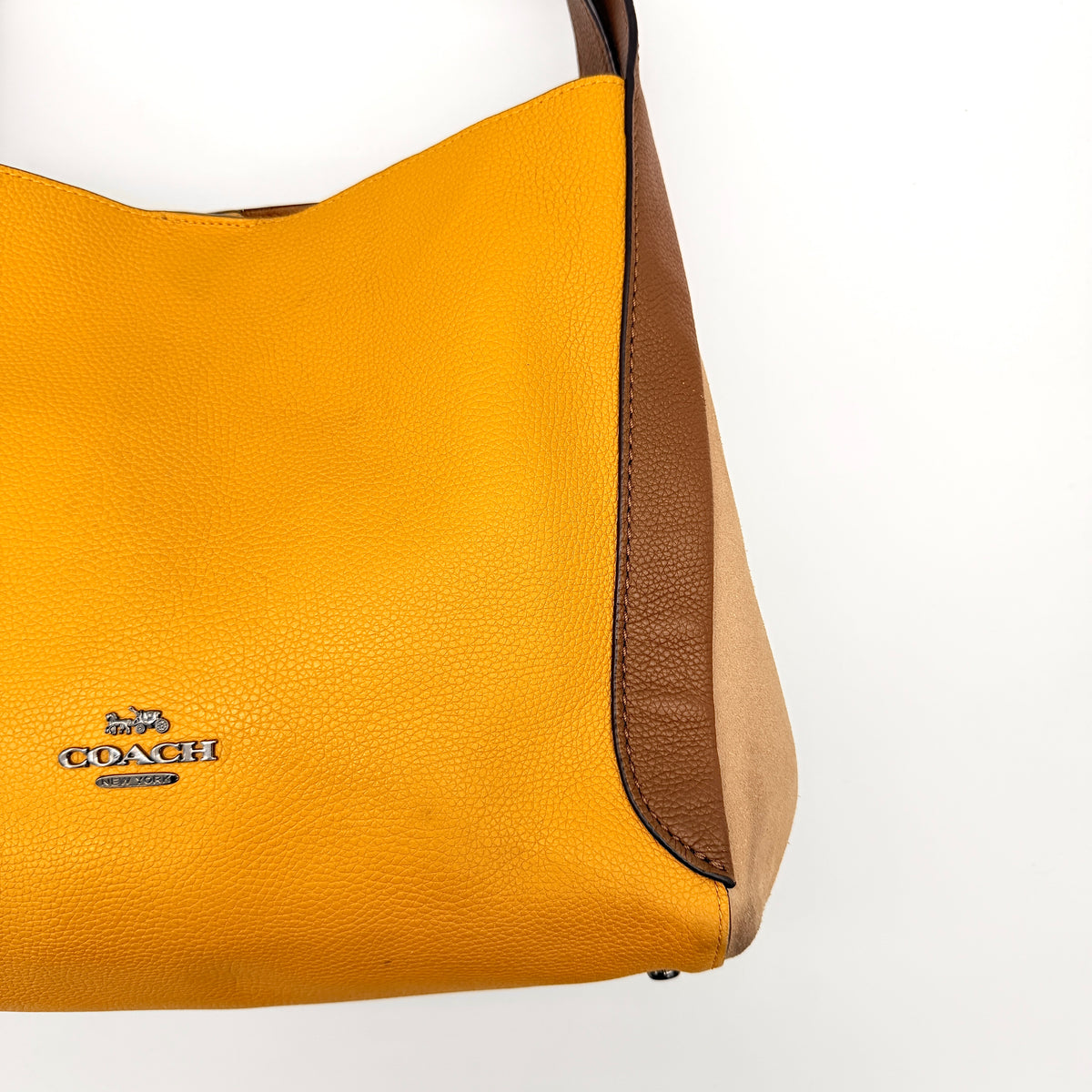 Coach Hadley Colorblock Hobo bag in yellow and brown leather with double top handles and suede side panels, shown against a white background.