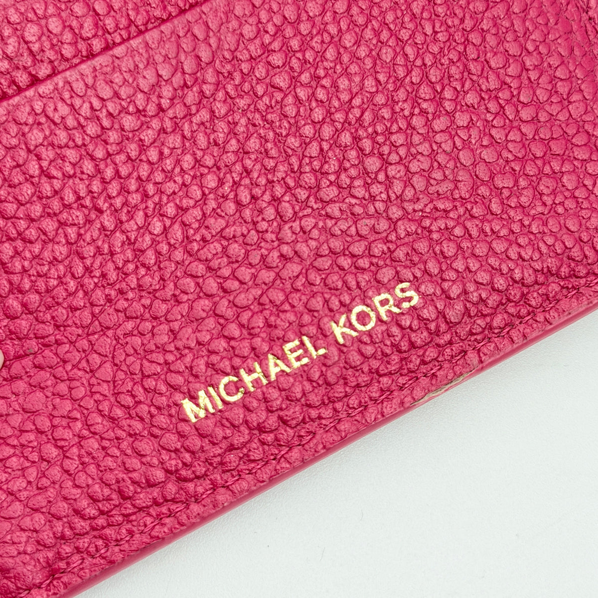 Michael Kors pink leather envelope trifold wallet with gold MK logo, shown closed on a white background.