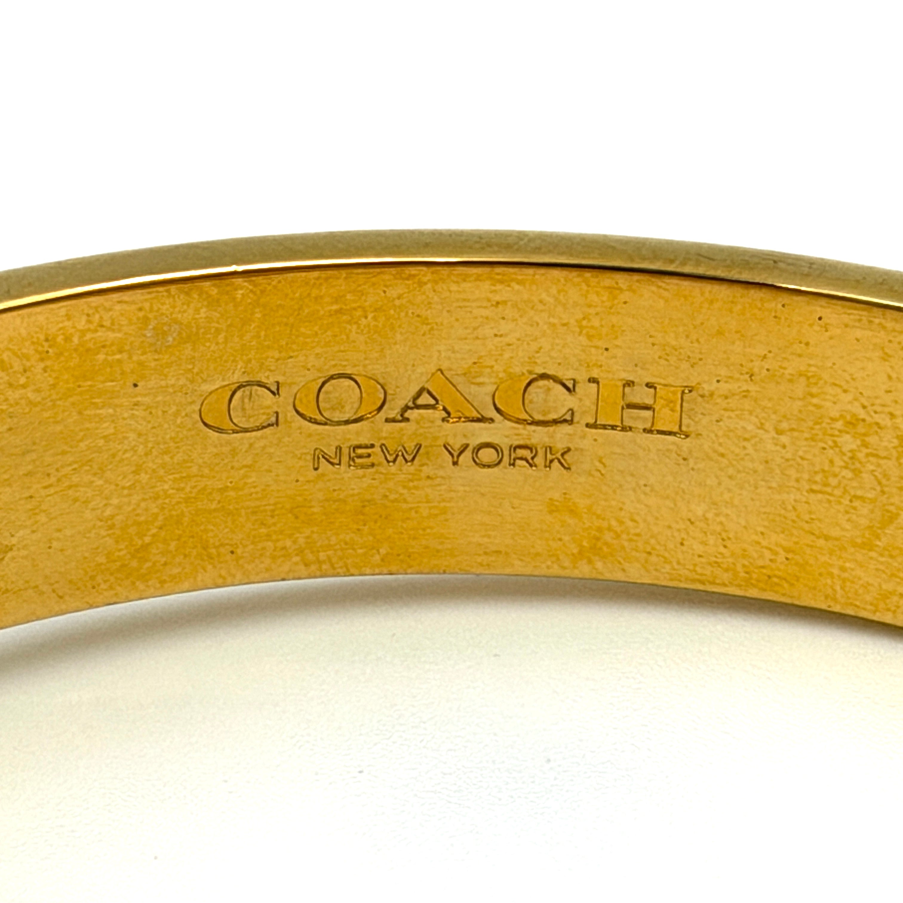 Coach Signature C Bangle Bracelet in gold-tone metal with red enamel, featuring the signature C motif and safety chain.