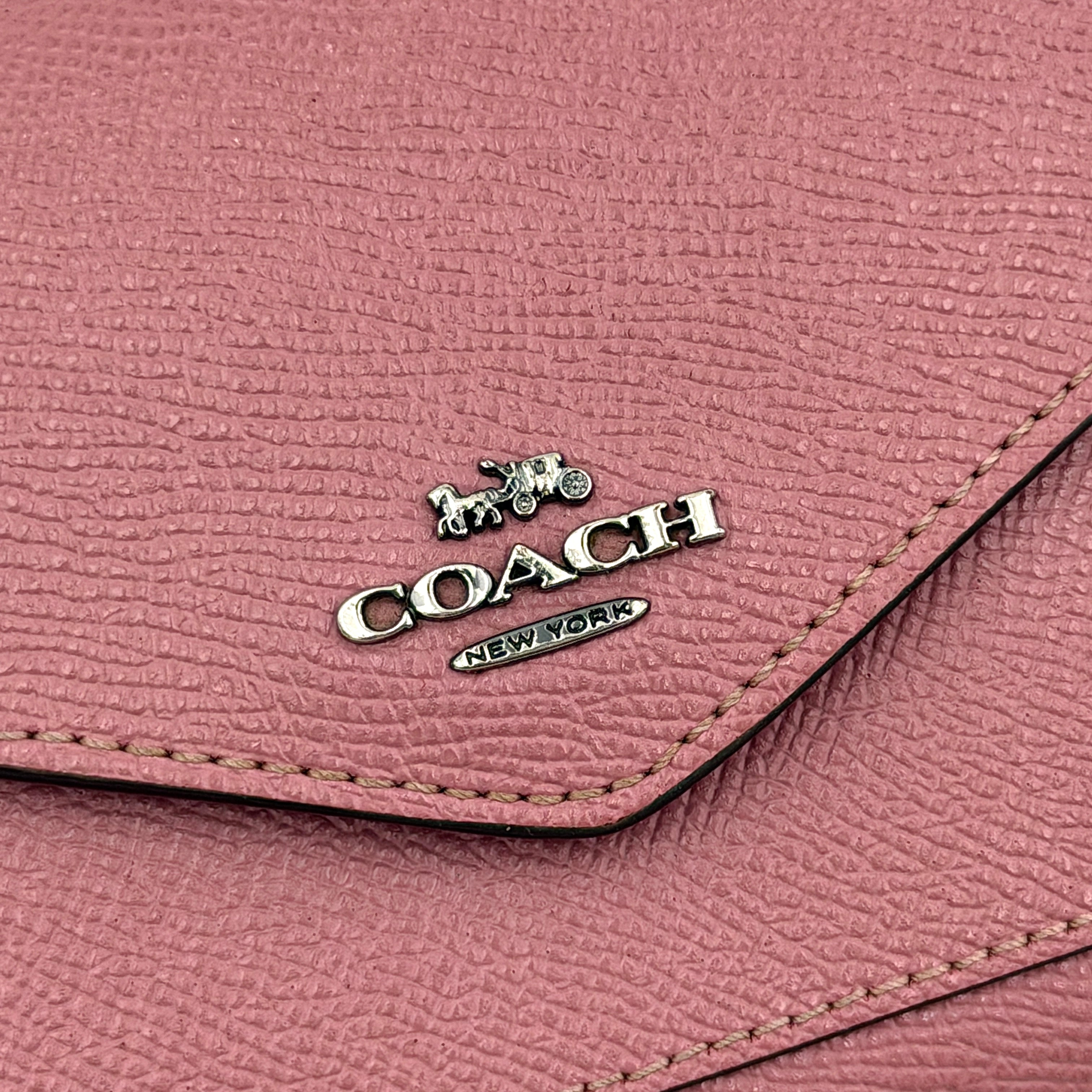 Coach Envelope Small Wallet in dusky pink grained leather with silver hardware and an angular flap closure.