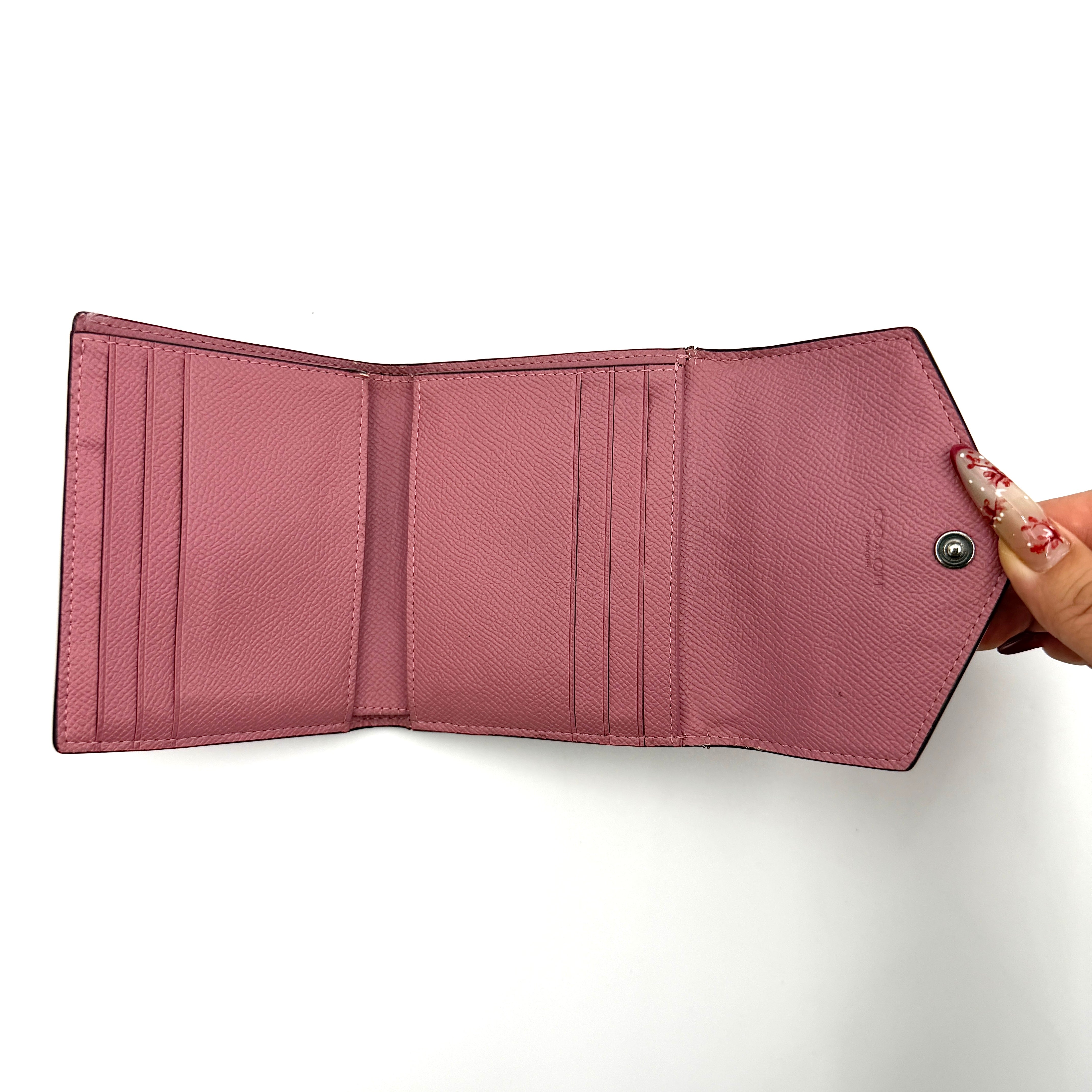 Coach Envelope Small Wallet in dusky pink grained leather with silver hardware and an angular flap closure.