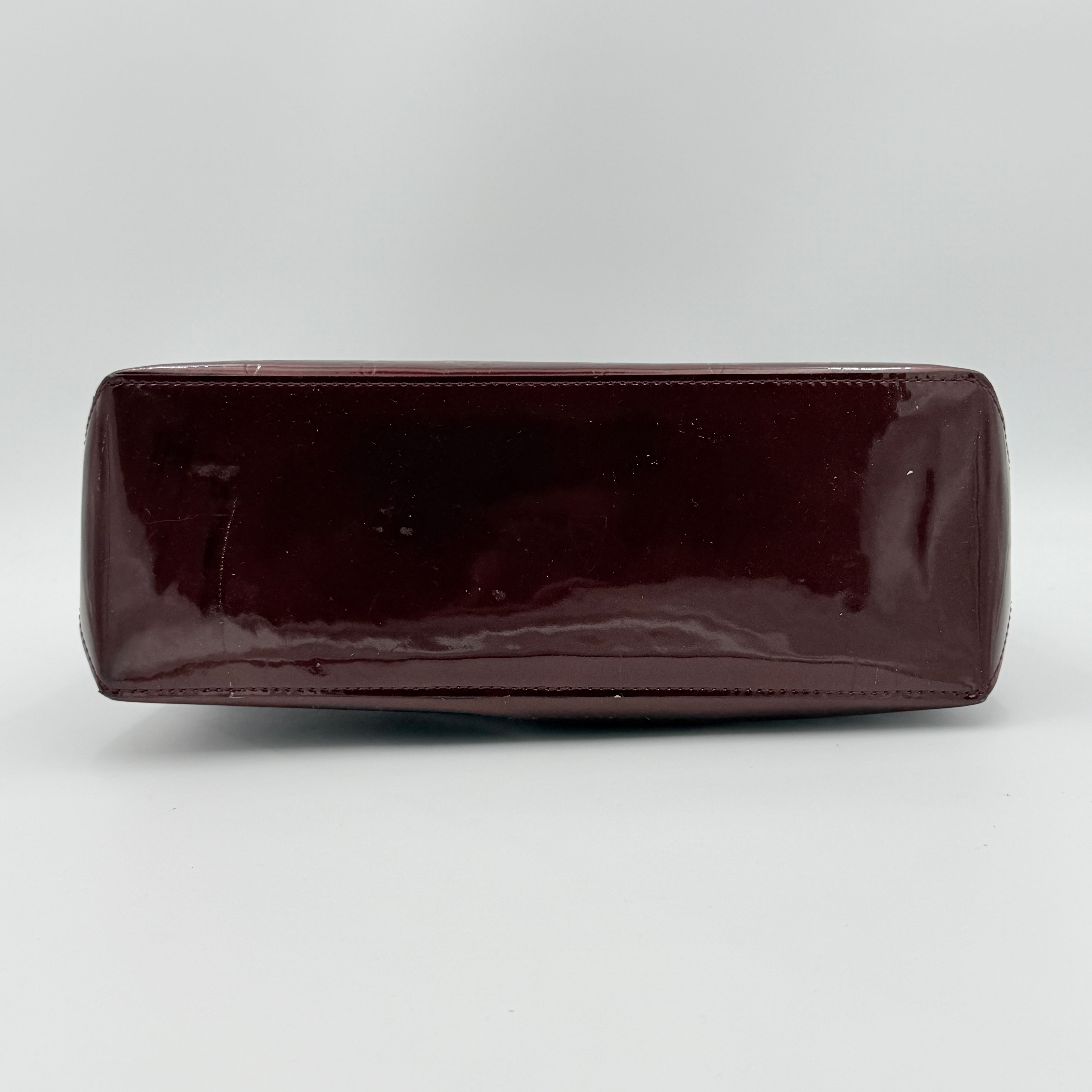 Louis Vuitton Wilshire PM Monogram Vernis bag in glossy deep red with gold nameplate and embossed monogram, displayed against a clean background.