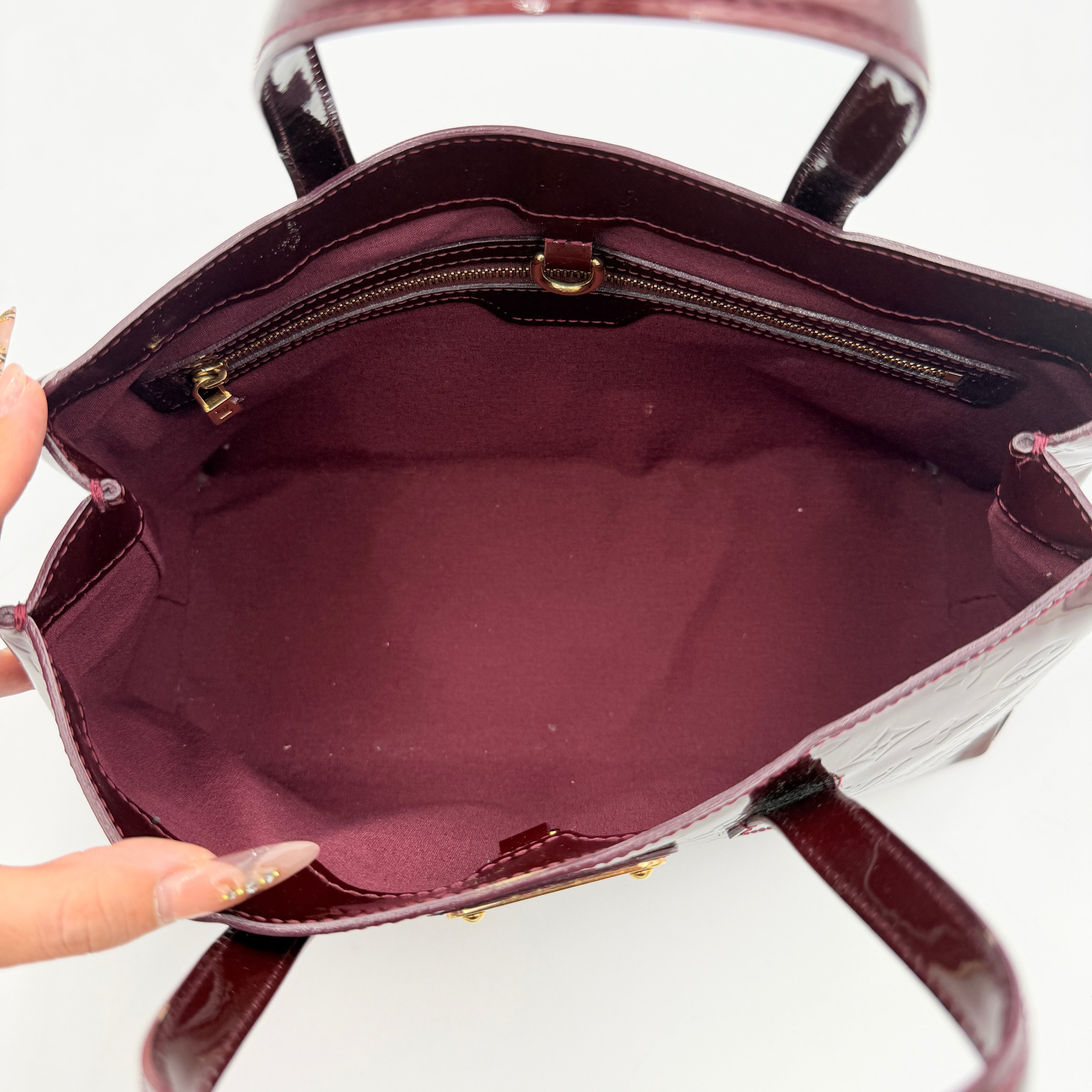 Louis Vuitton Wilshire PM Monogram Vernis bag in glossy deep red with gold nameplate and embossed monogram, displayed against a clean background.