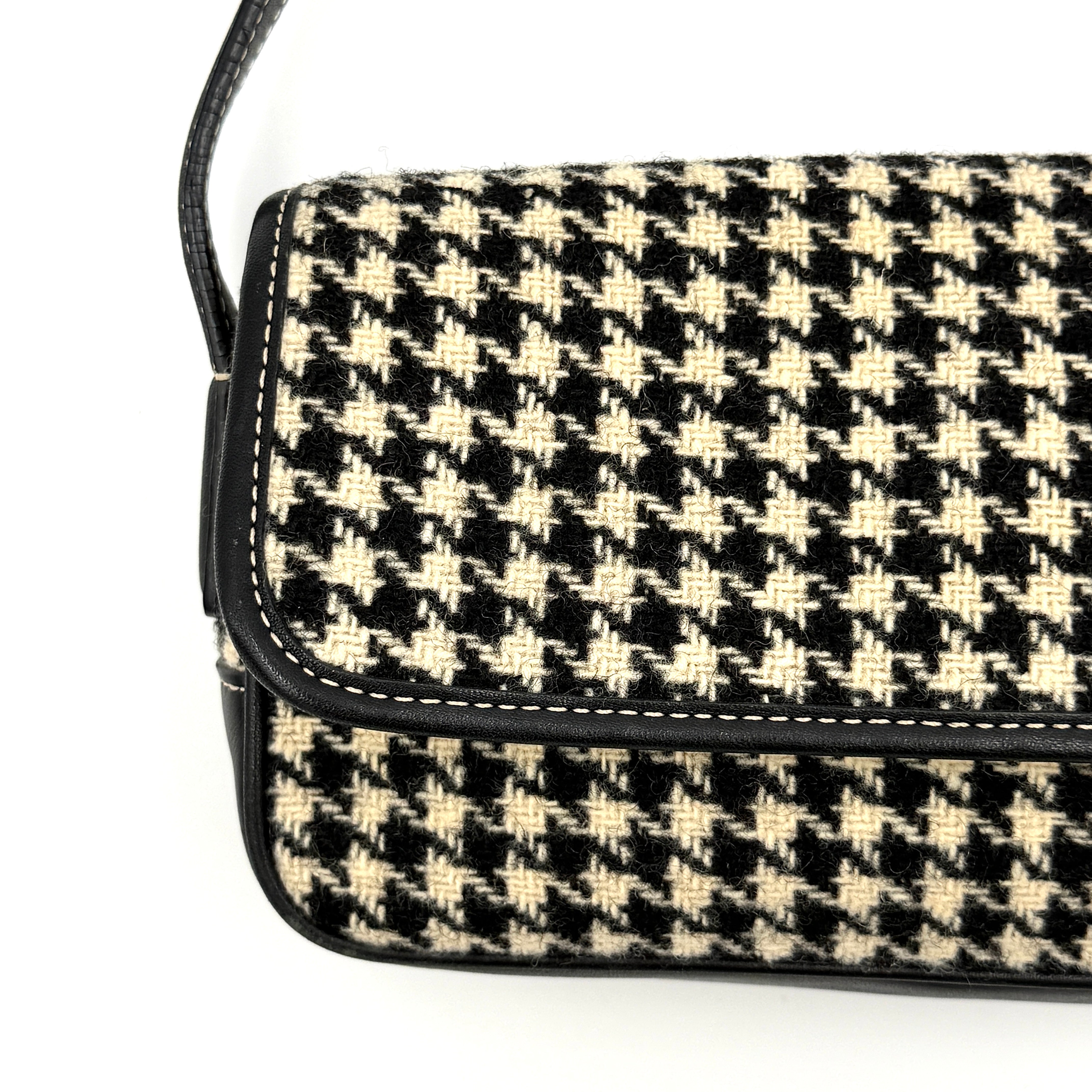Coach Y2K shoulder bag with a bold black and cream houndstooth pattern and sleek leather trim.