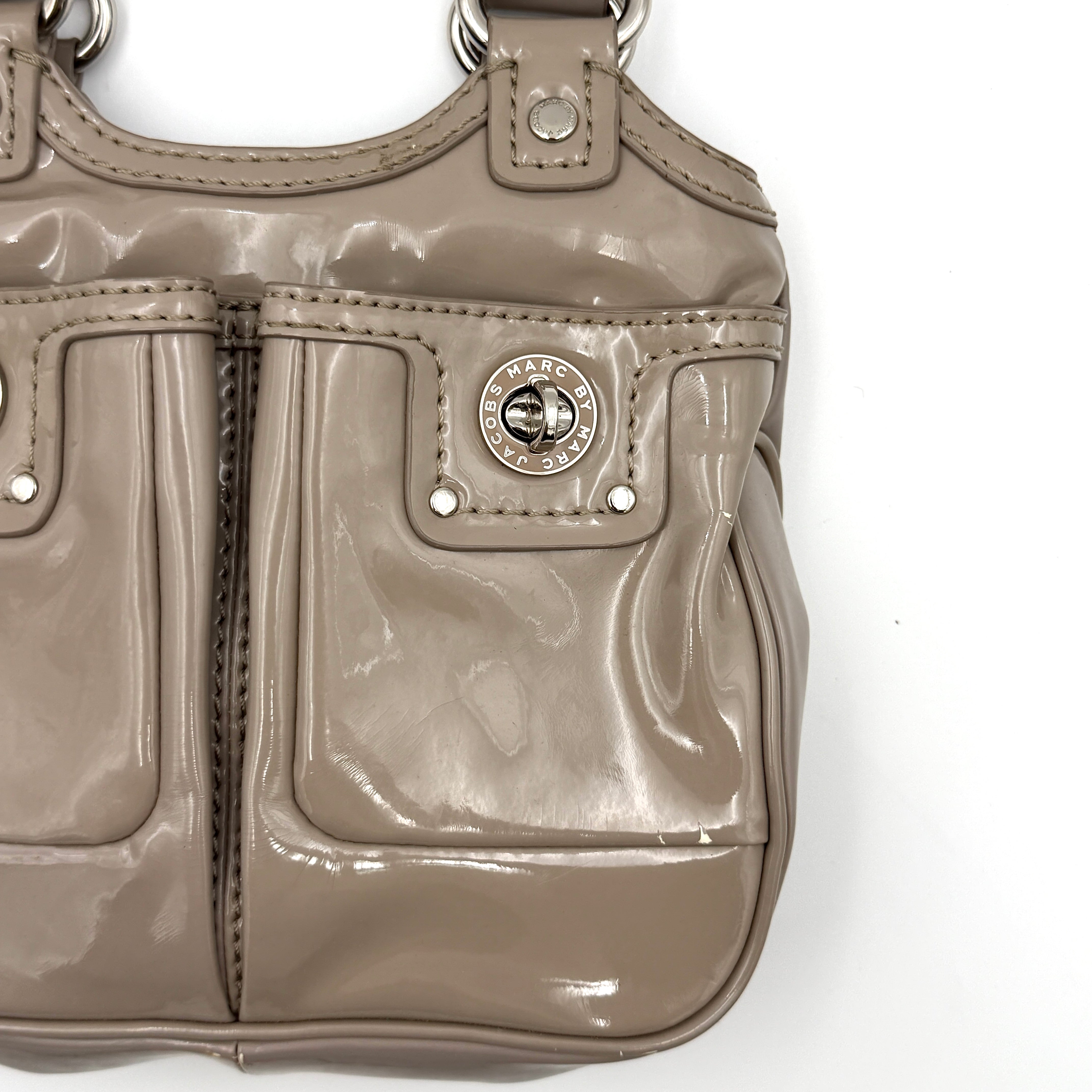 Marc Jacobs grey patent leather shoulder bag with double front turnlock pockets and structured dual handles.