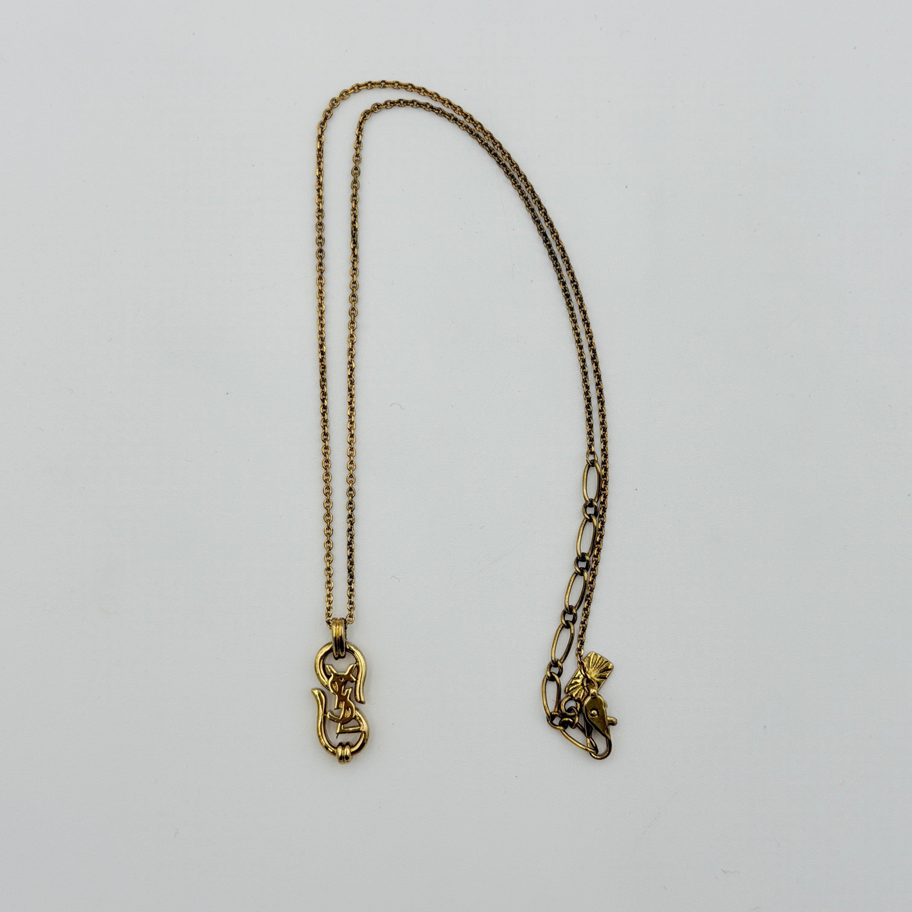 Saint Laurent Cassandre Logo Necklace in gold metal with signature YSL pendant displayed on a necklace stand.