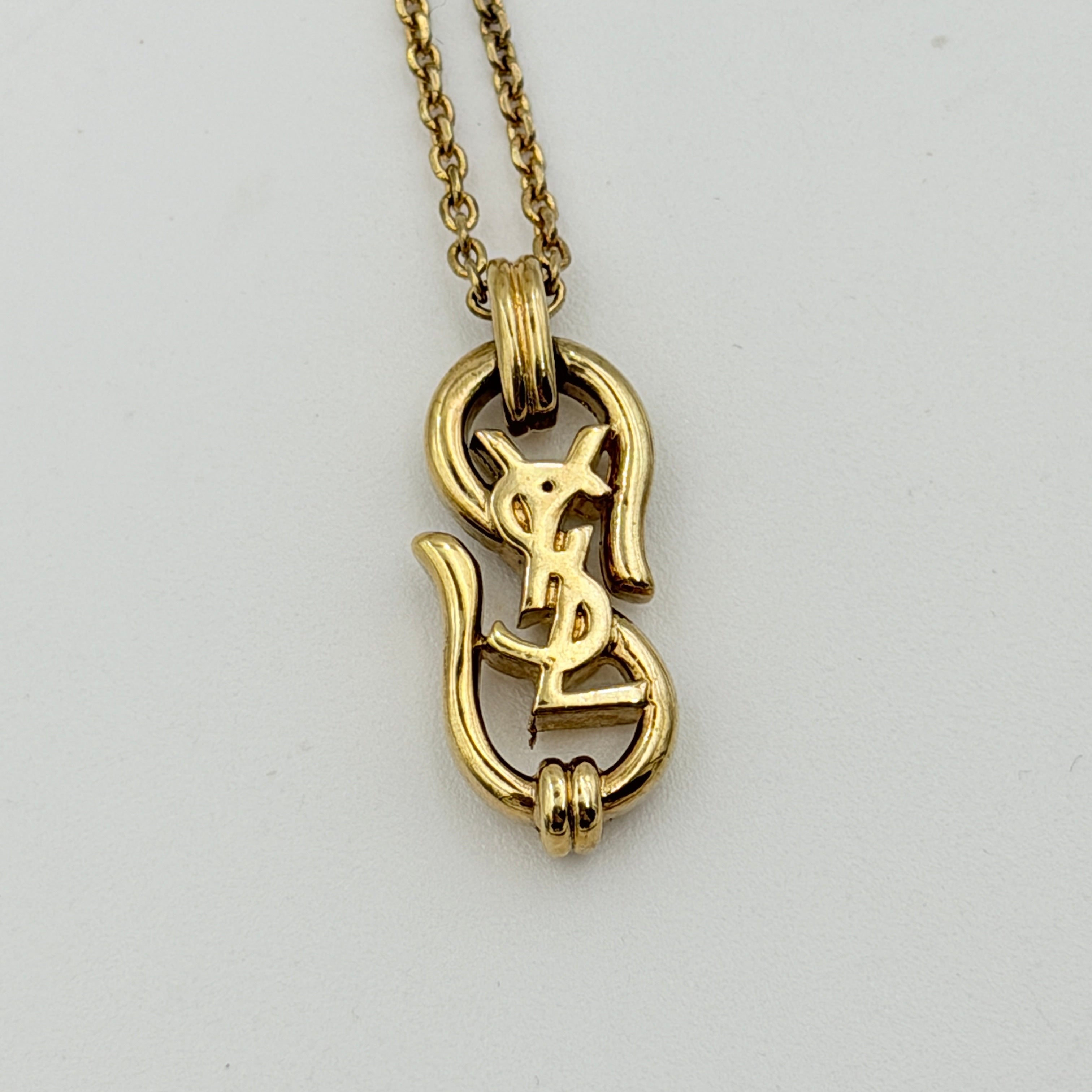 Saint Laurent Cassandre Logo Necklace in gold metal with signature YSL pendant displayed on a necklace stand.