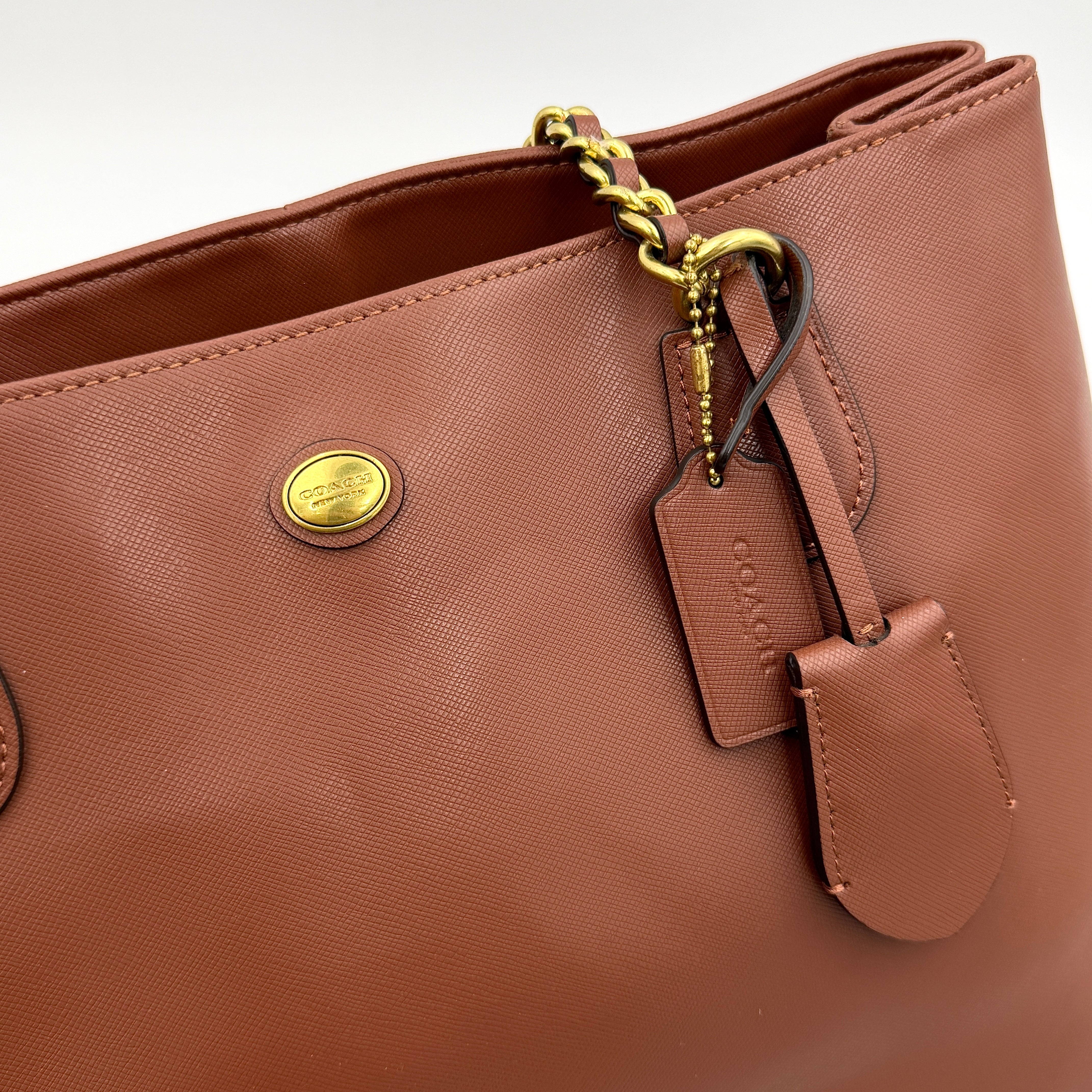 Coach Peyton Chain Shoulder Bag in brown leather with gold-tone chain handles, styled against a clean background.