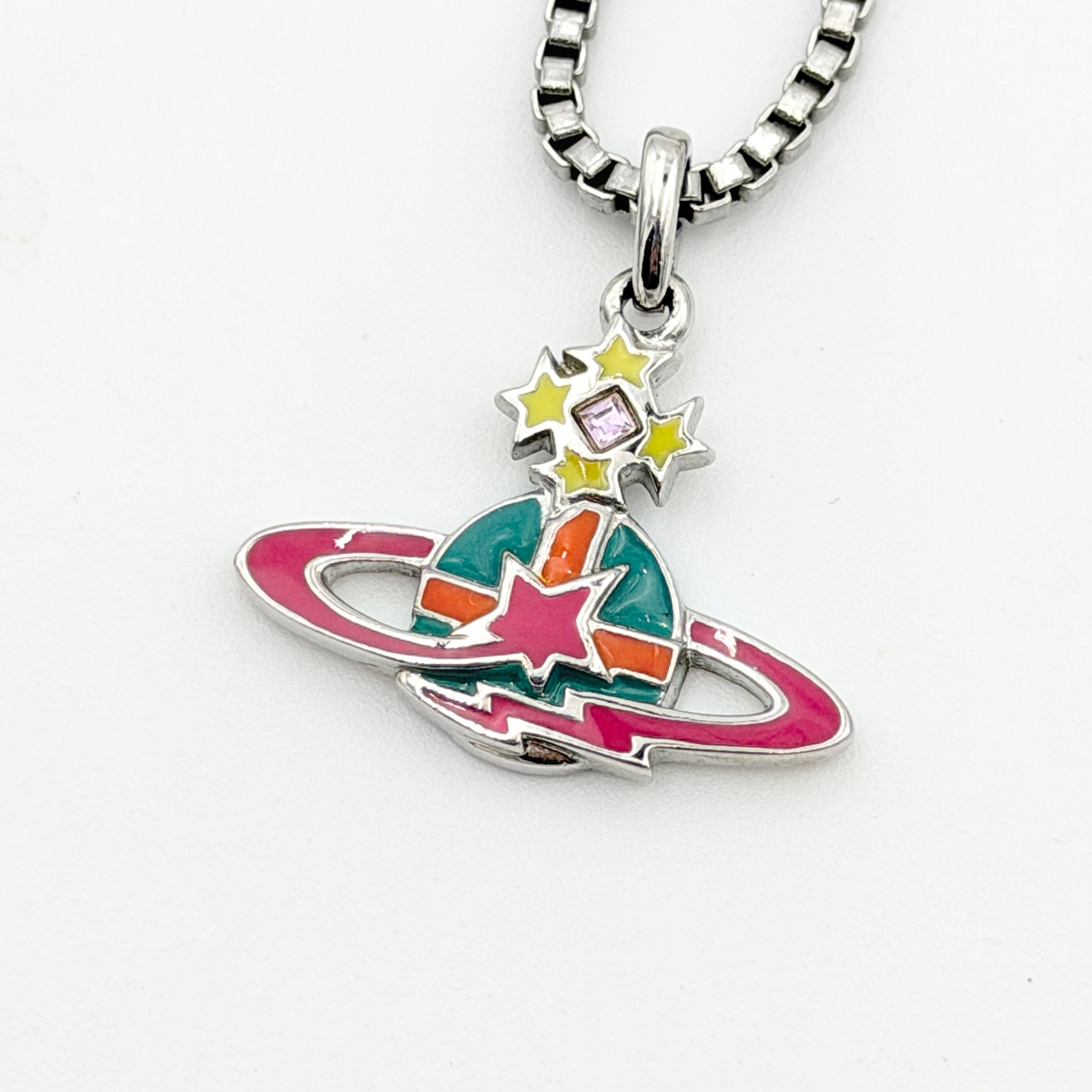 Vivienne Westwood Shooting Star Orb Necklace in silver with vibrant multi-coloured enamel details displayed on a cream jewellery stand.