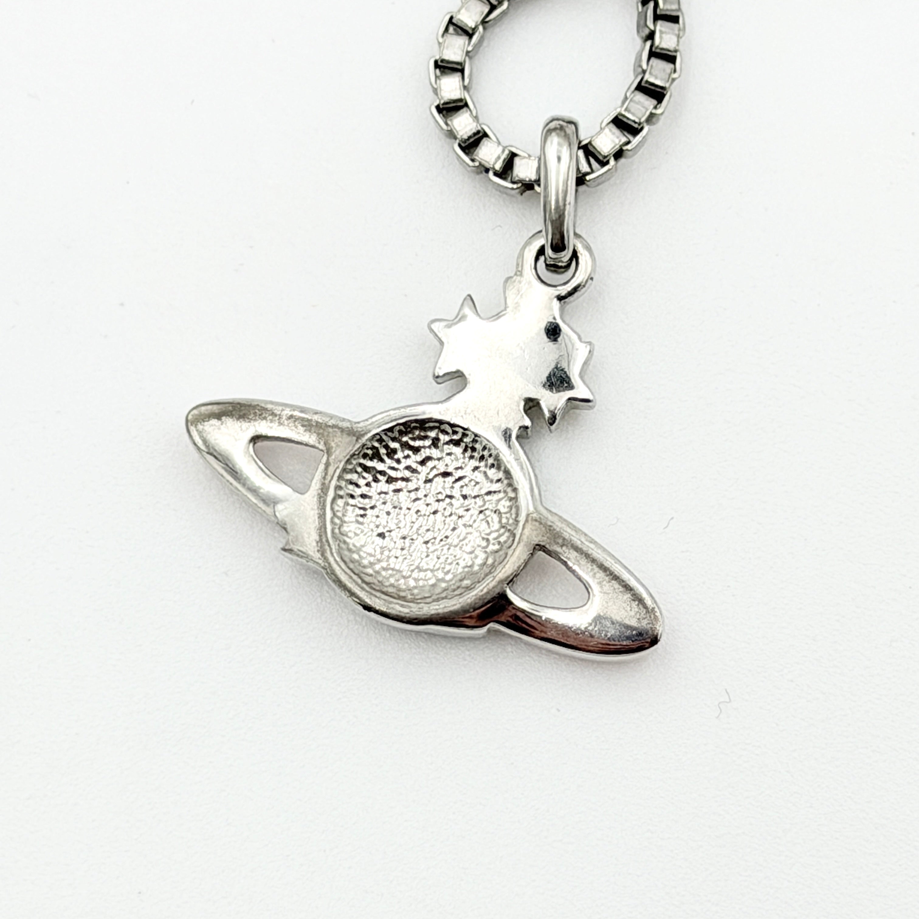 Vivienne Westwood Shooting Star Orb Necklace in silver with vibrant multi-coloured enamel details displayed on a cream jewellery stand.