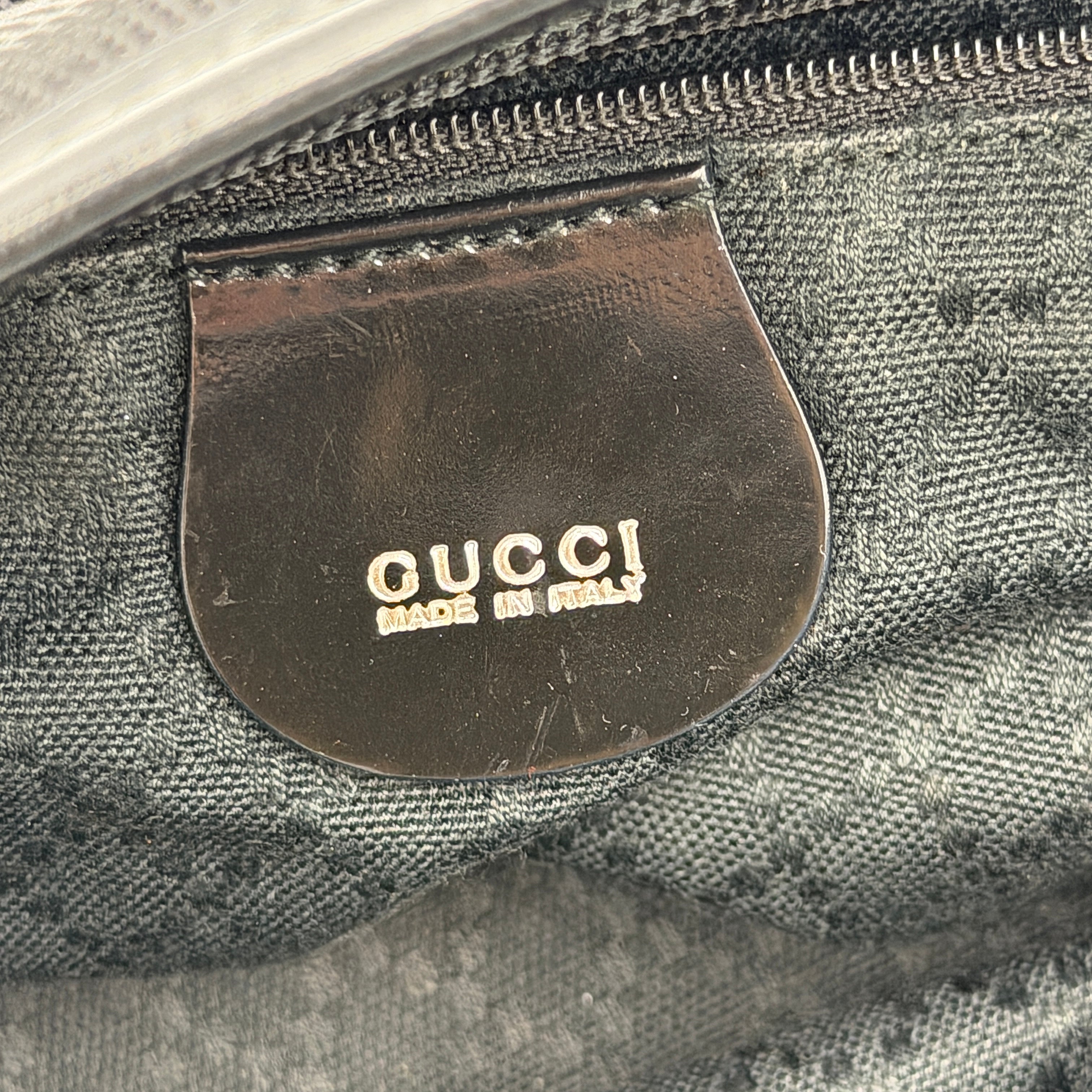 A classic black Gucci nylon tote bag with leather handles and gold-tone hardware displayed upright against a clean background.