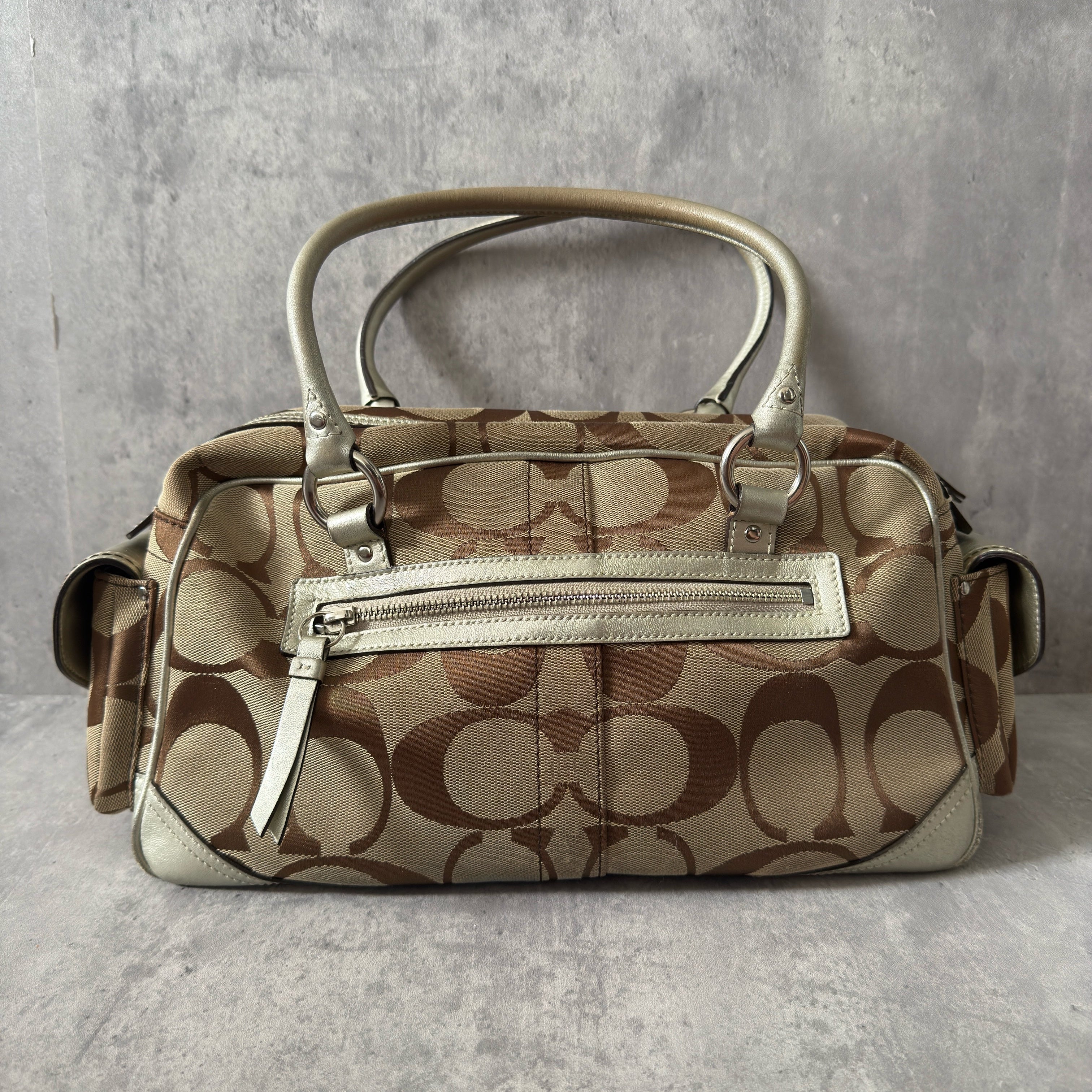 Coach 2Way Poppy Signature Bag in beige monogram canvas with silver leather trim, featuring double handles, turn-lock front pockets, and a spacious interior.