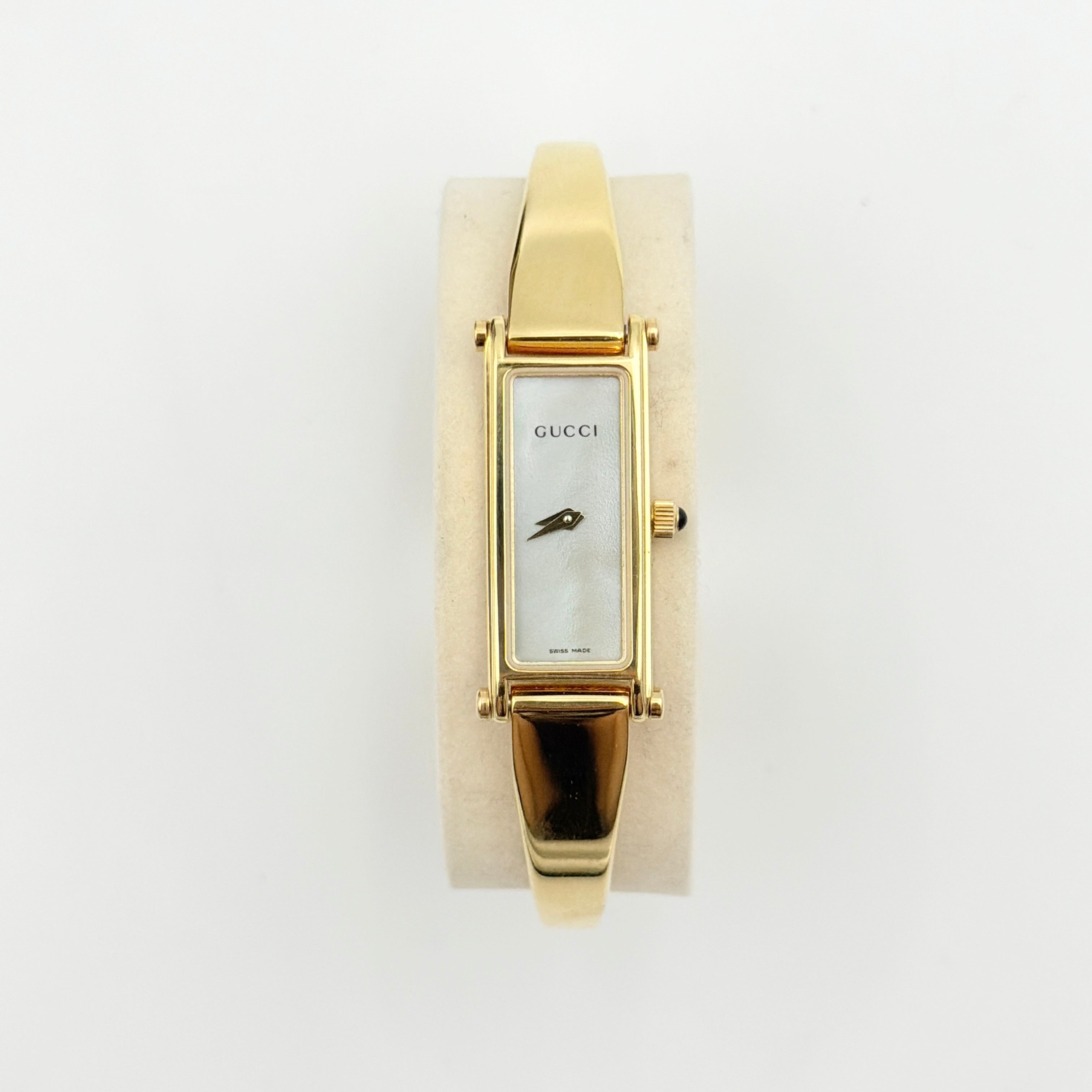 Gucci 1500L gold-tone quartz watch with white rectangular dial, displayed in box with warranty card.
