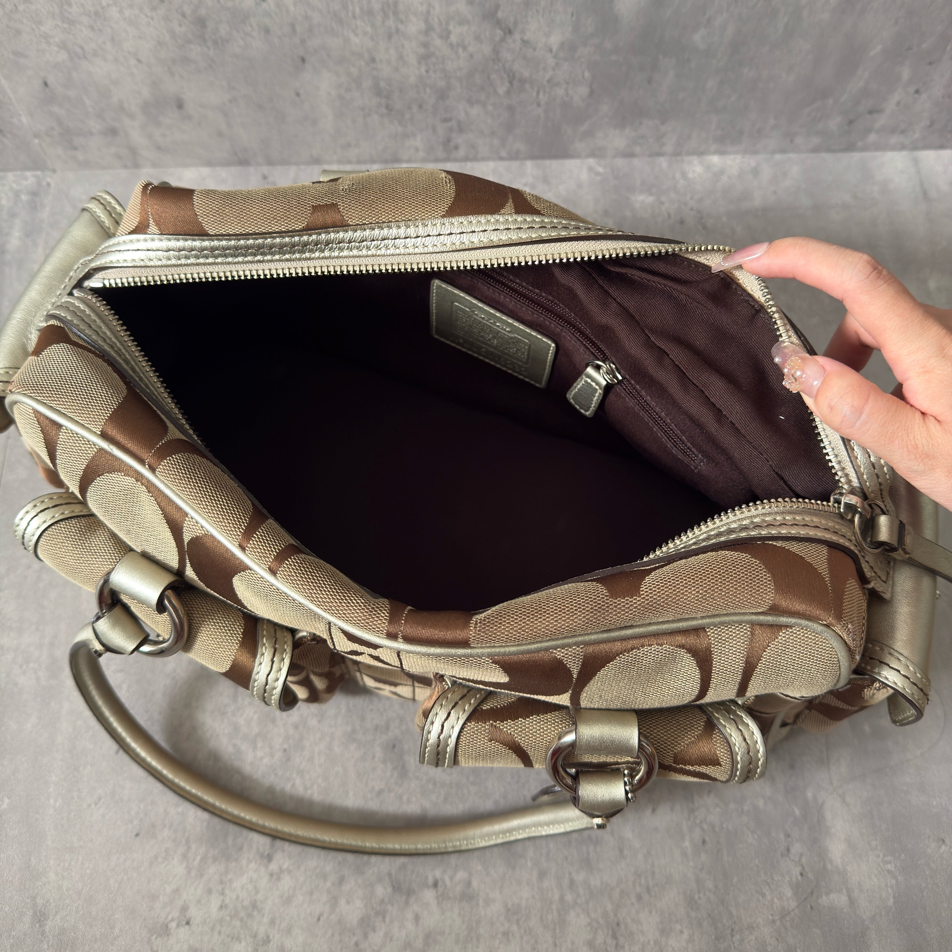 Coach 2Way Poppy Signature Bag in beige monogram canvas with silver leather trim, featuring double handles, turn-lock front pockets, and a spacious interior.