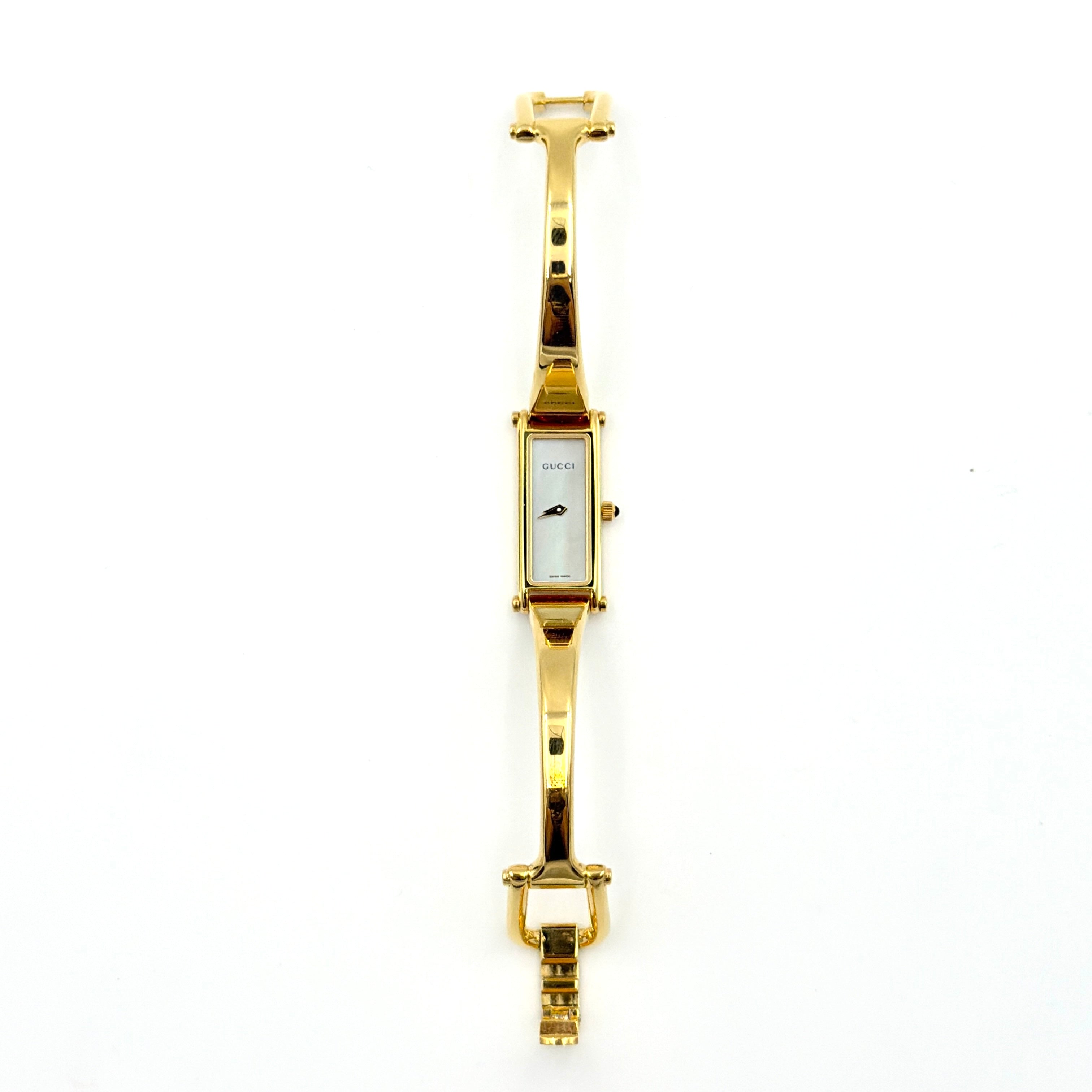 Gucci 1500L gold-tone quartz watch with white rectangular dial, displayed in box with warranty card.