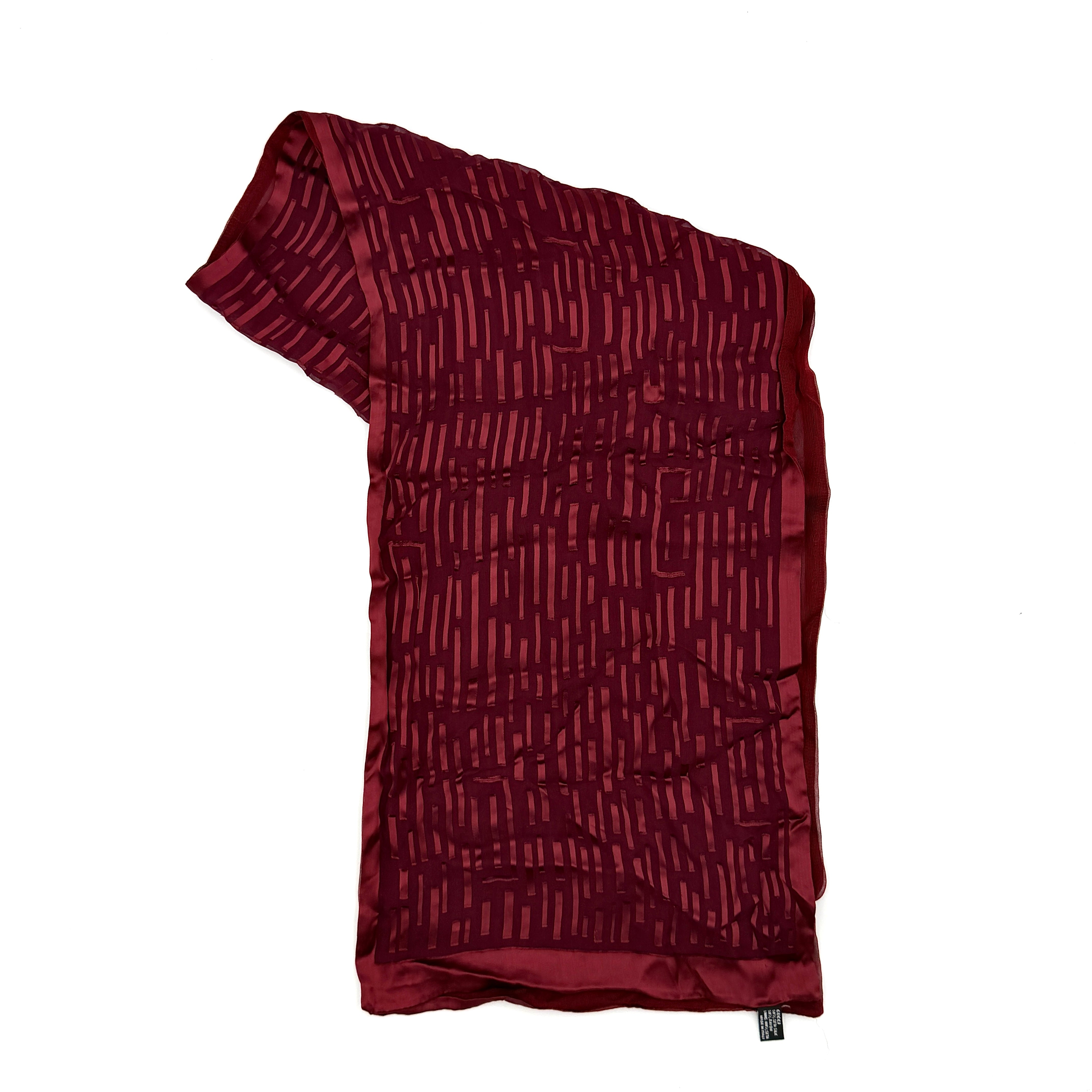 A maroon Gucci silk scarf with a tonal geometric jacquard pattern and a lustrous silk border, elegantly displayed to highlight its texture.
