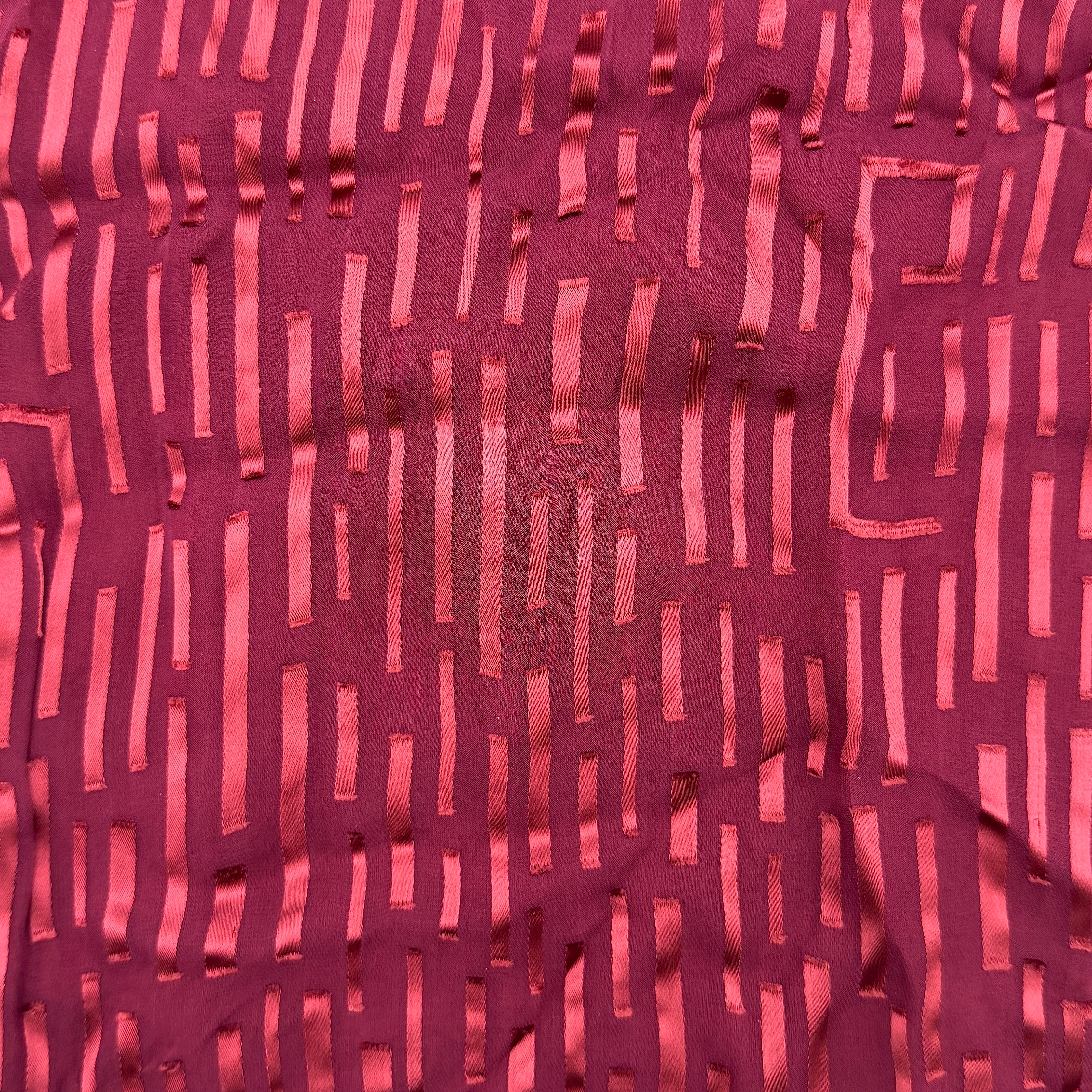 A maroon Gucci silk scarf with a tonal geometric jacquard pattern and a lustrous silk border, elegantly displayed to highlight its texture.