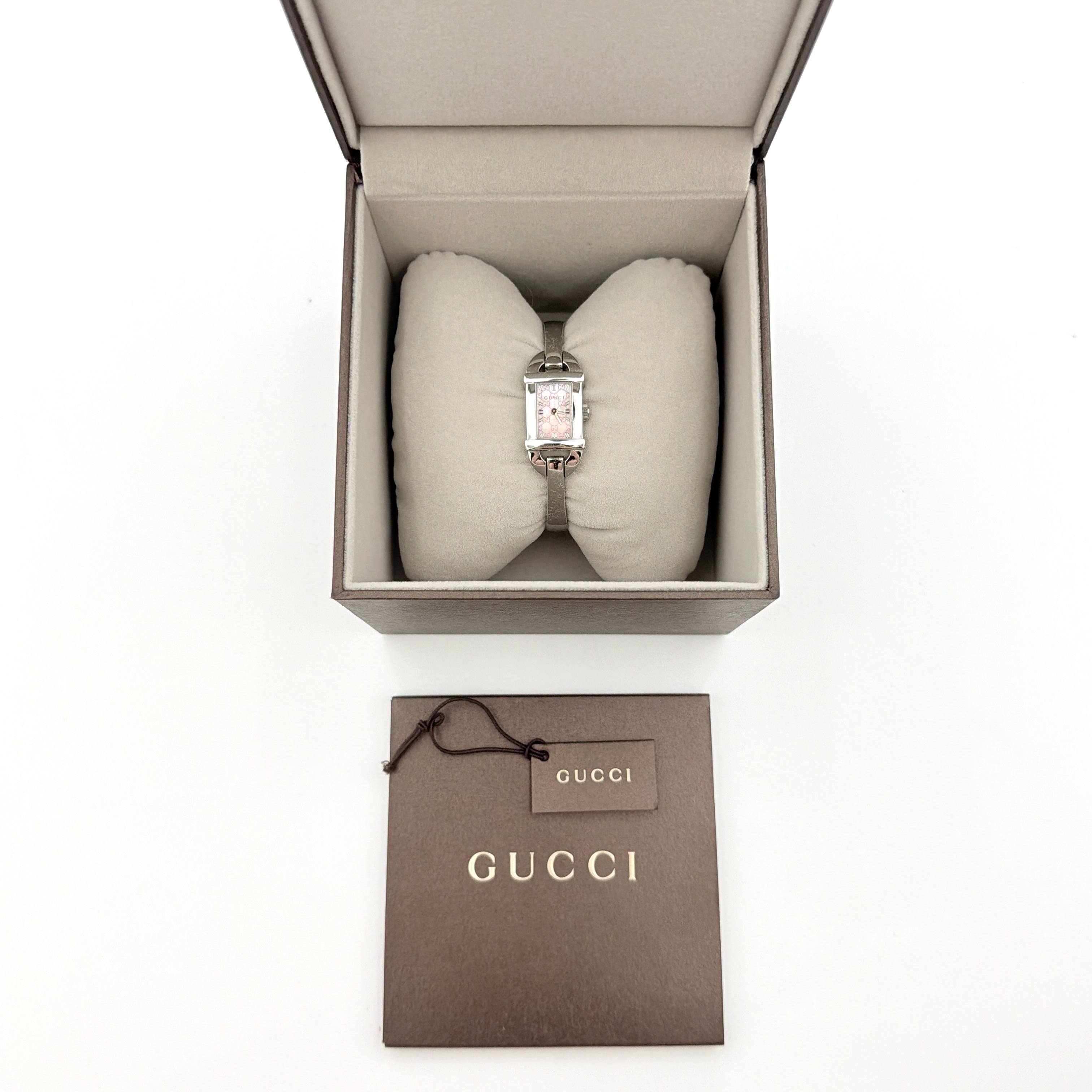 Gucci 6800L GG Bangle Watch in stainless steel with a pink monogram dial, displayed in its original box with branded booklet.