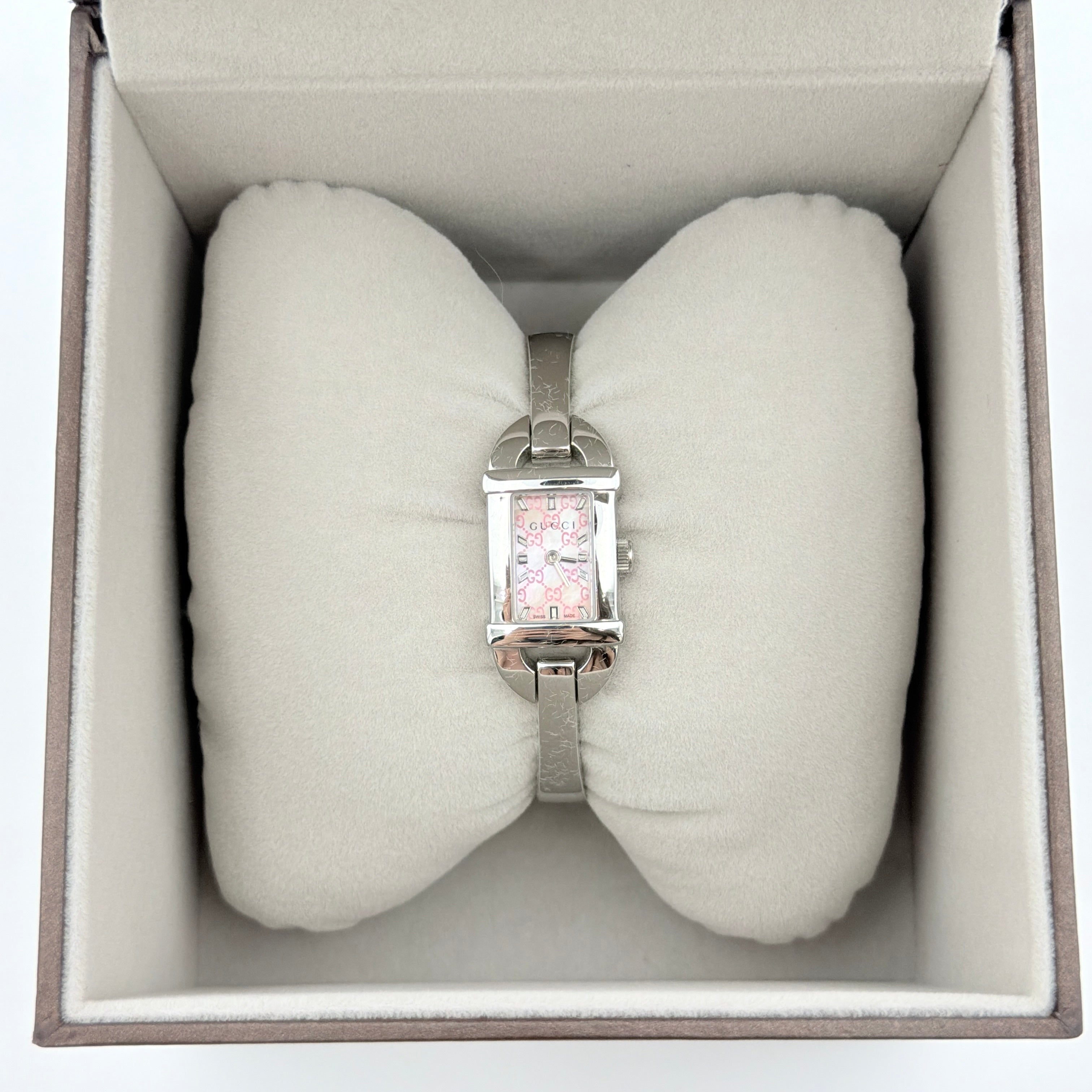 Gucci 6800L GG Bangle Watch in stainless steel with a pink monogram dial, displayed in its original box with branded booklet.