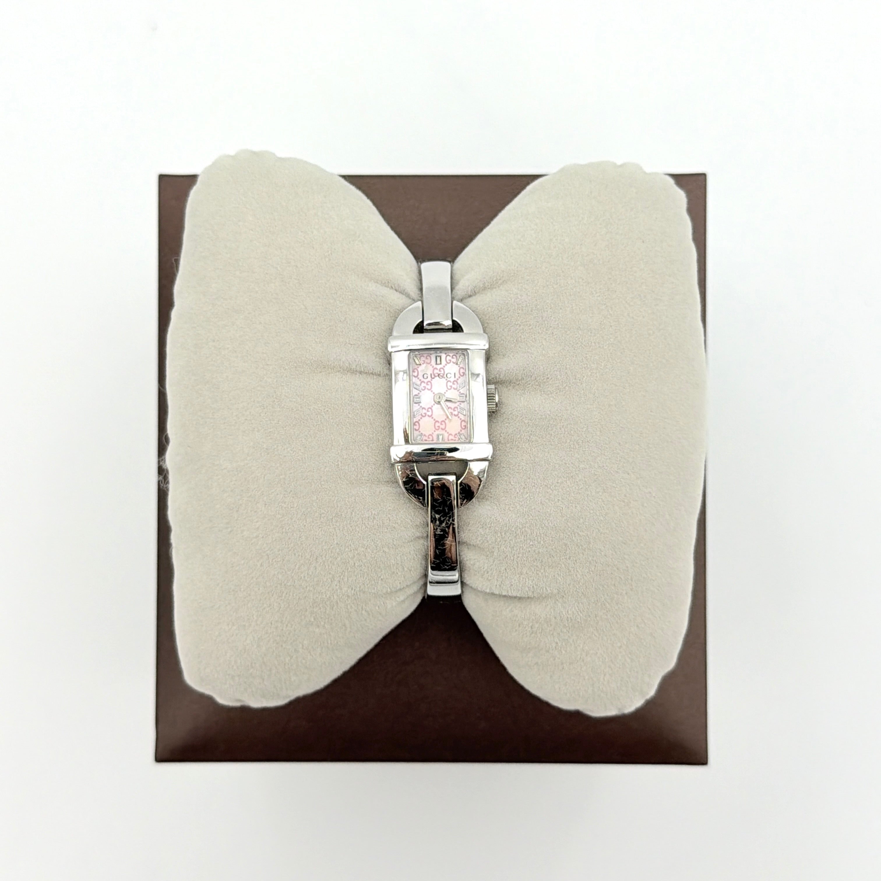 Gucci 6800L GG Bangle Watch in stainless steel with a pink monogram dial, displayed in its original box with branded booklet.