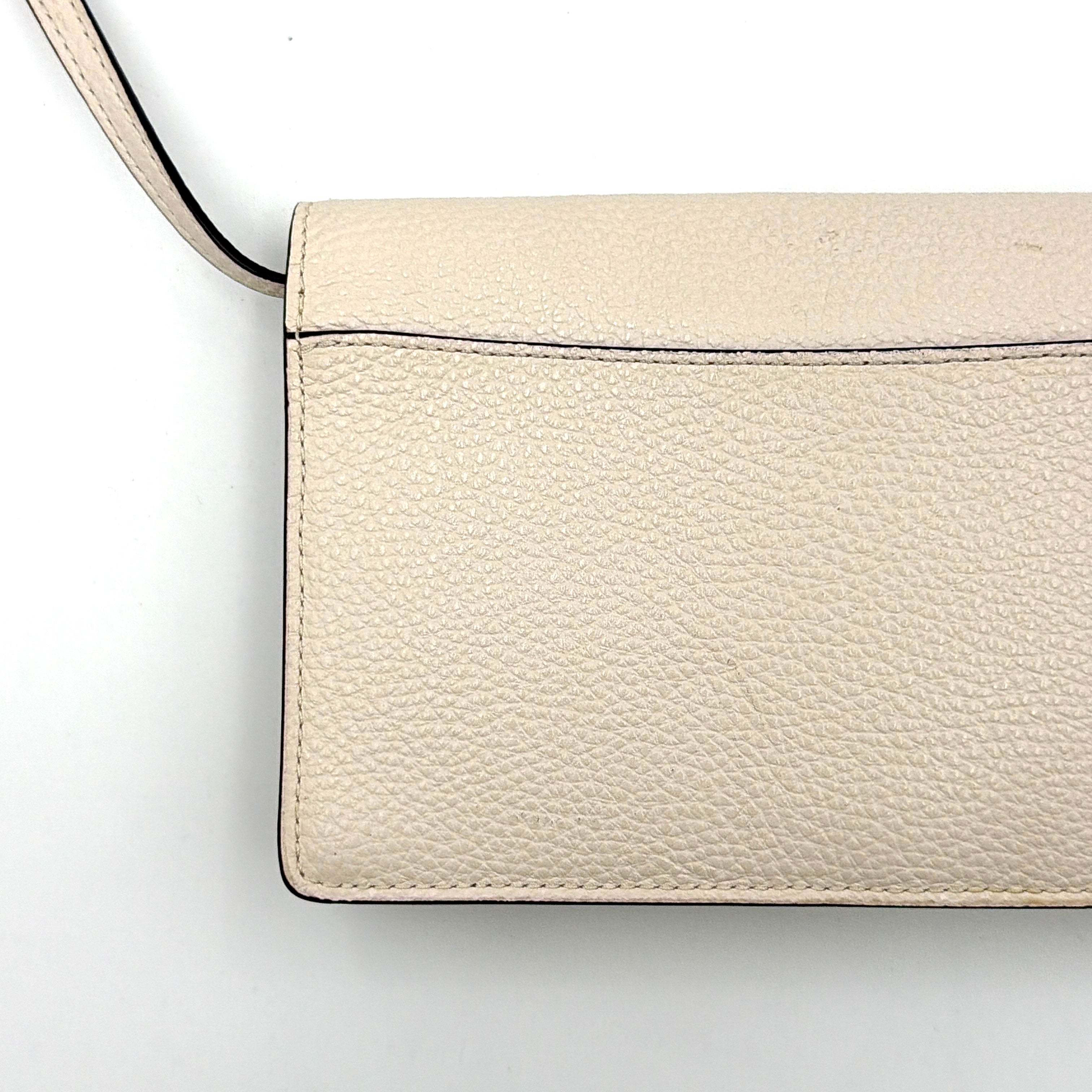 Coach x Disney Dumbo cream foldover crossbody bag with Dumbo illustration and slender strap, displayed against white background.