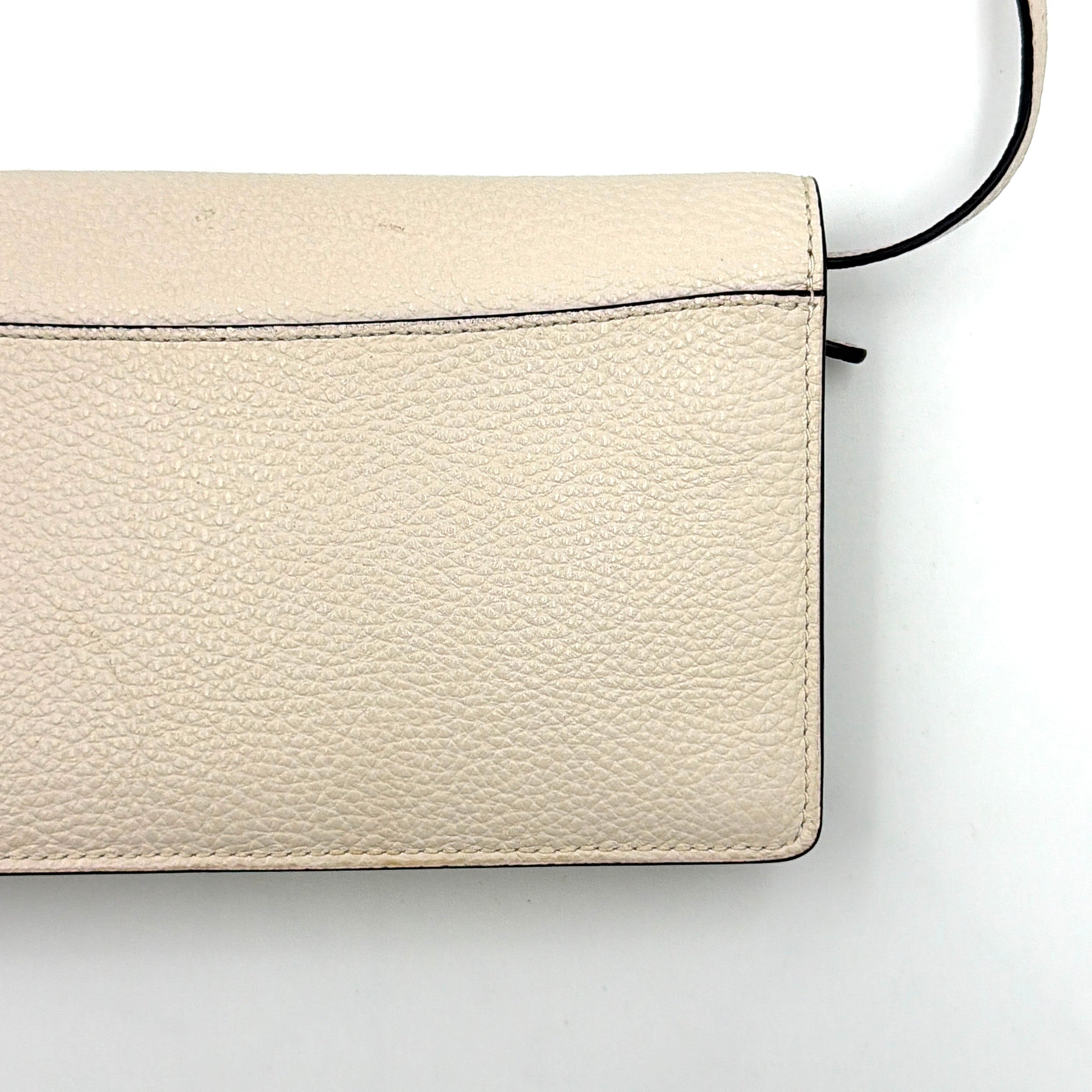 Coach x Disney Dumbo cream foldover crossbody bag with Dumbo illustration and slender strap, displayed against white background.