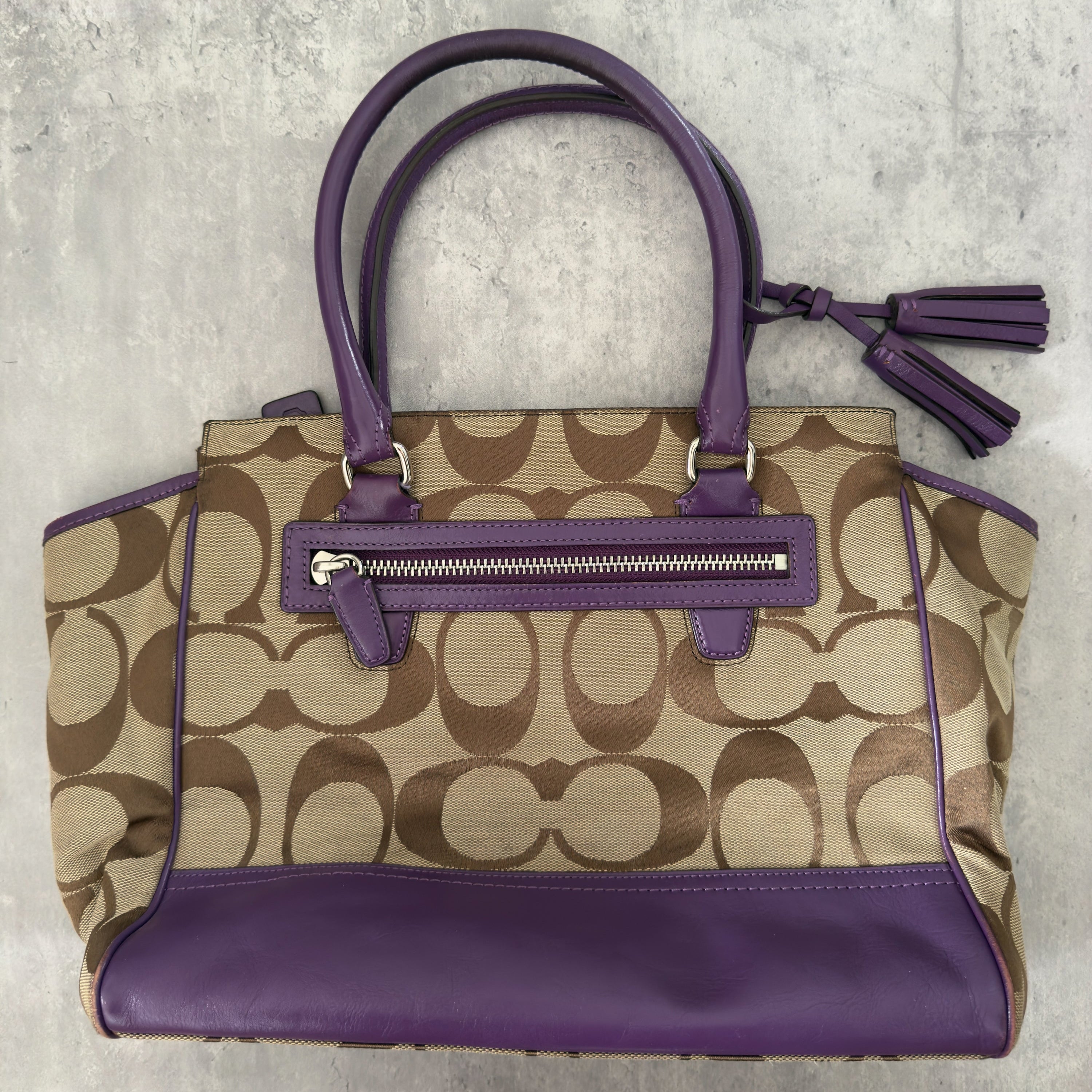 Coach Signature Legacy Candace Carry-All handbag in beige coated canvas with monogram print, purple leather trim, silver-tone hardware, and tassel details.