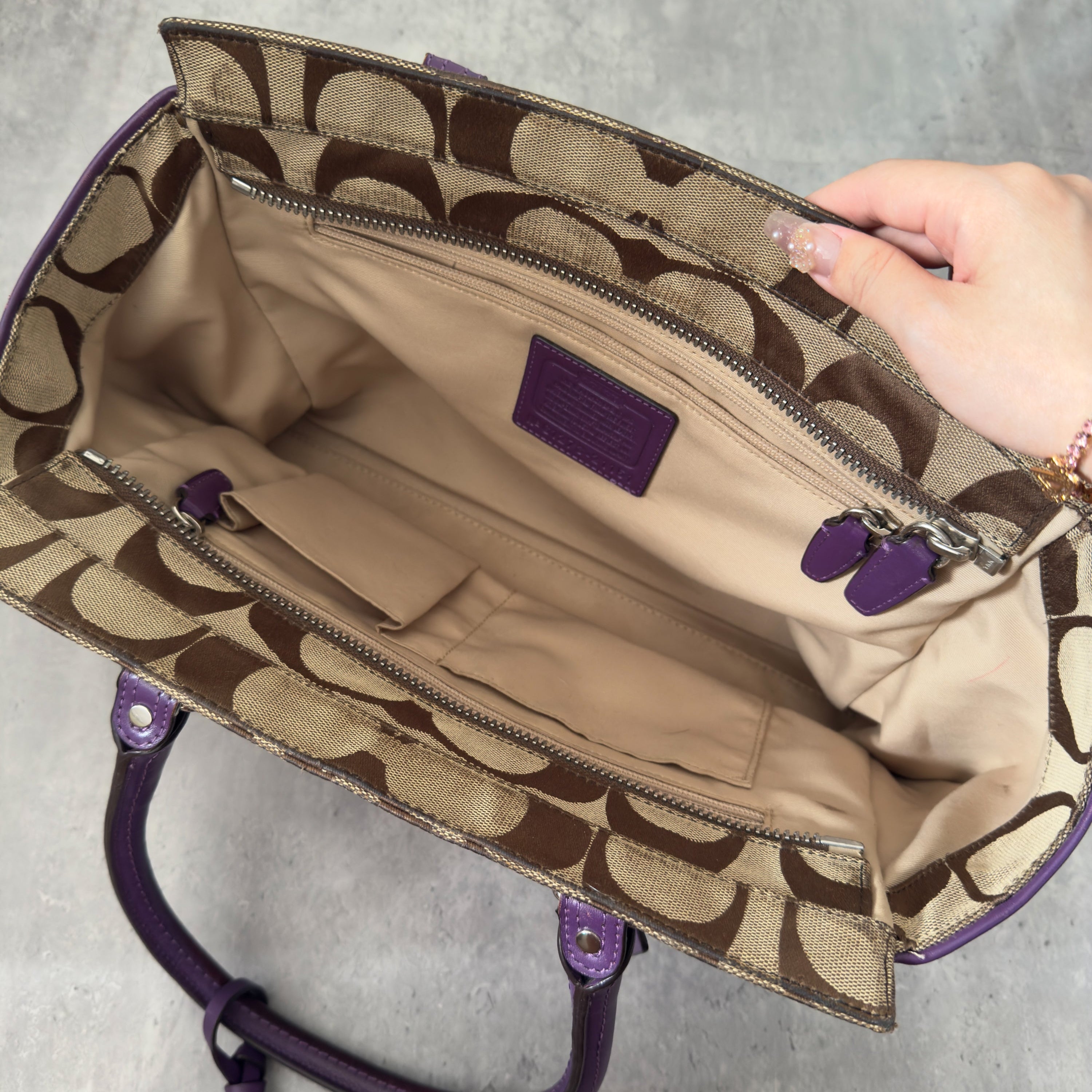 Coach Signature Legacy Candace Carry-All handbag in beige coated canvas with monogram print, purple leather trim, silver-tone hardware, and tassel details.