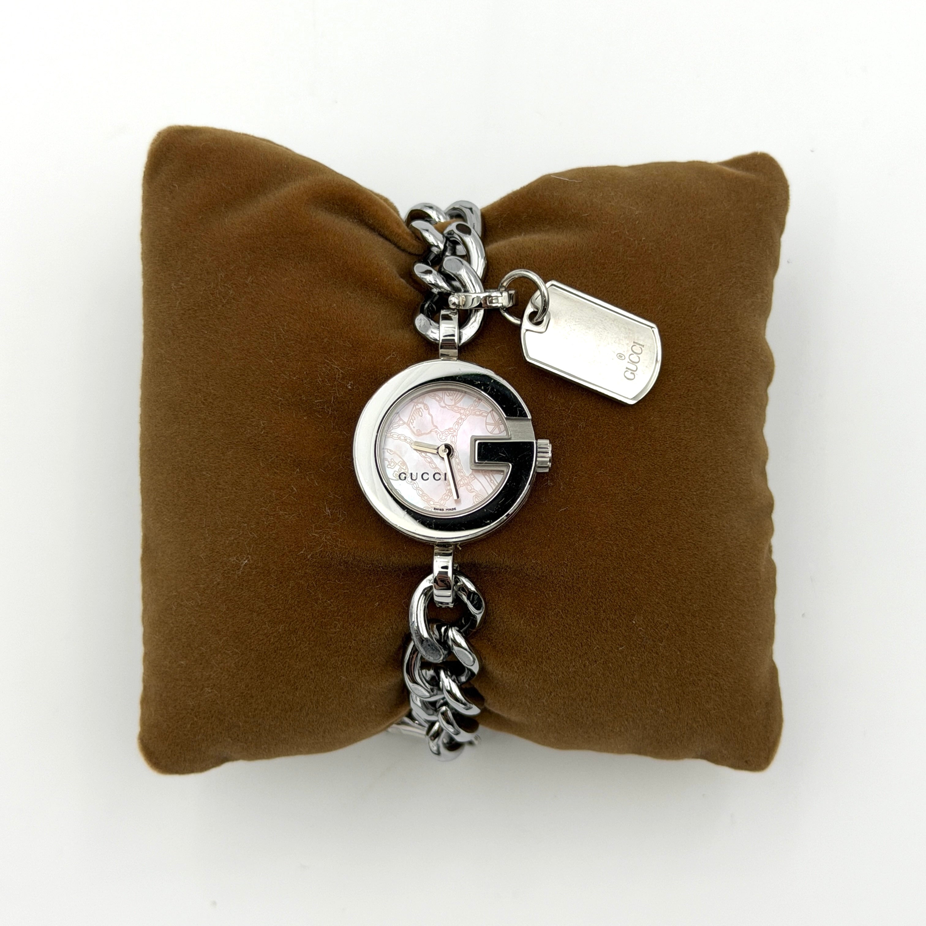 Gucci 107 G Charm Bracelet Watch with silver chunky chain and pink dial, styled on a brown cushion with original Gucci box.