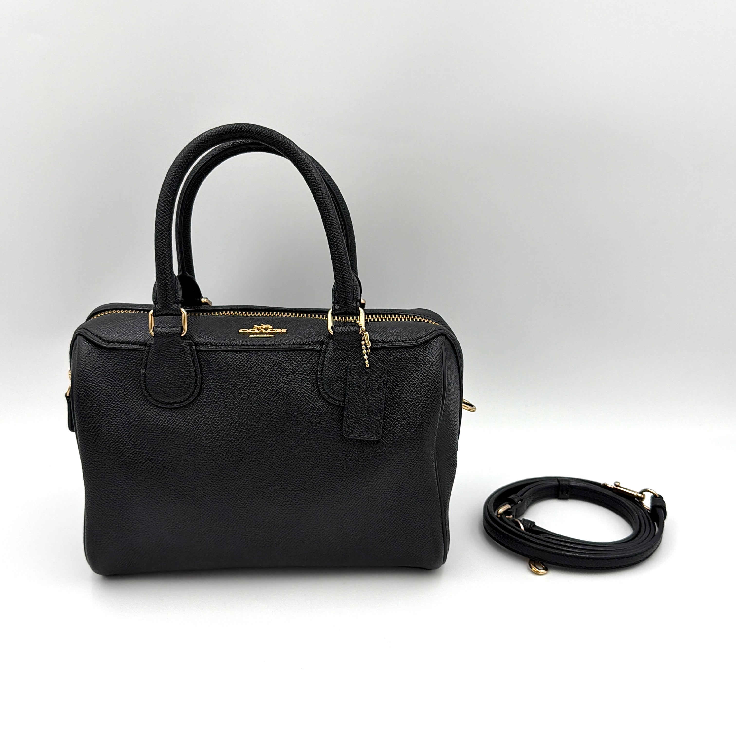 Coach Mini Bennett Boston Bag in black pebbled leather with gold hardware and detachable strap, styled against a clean backdrop.