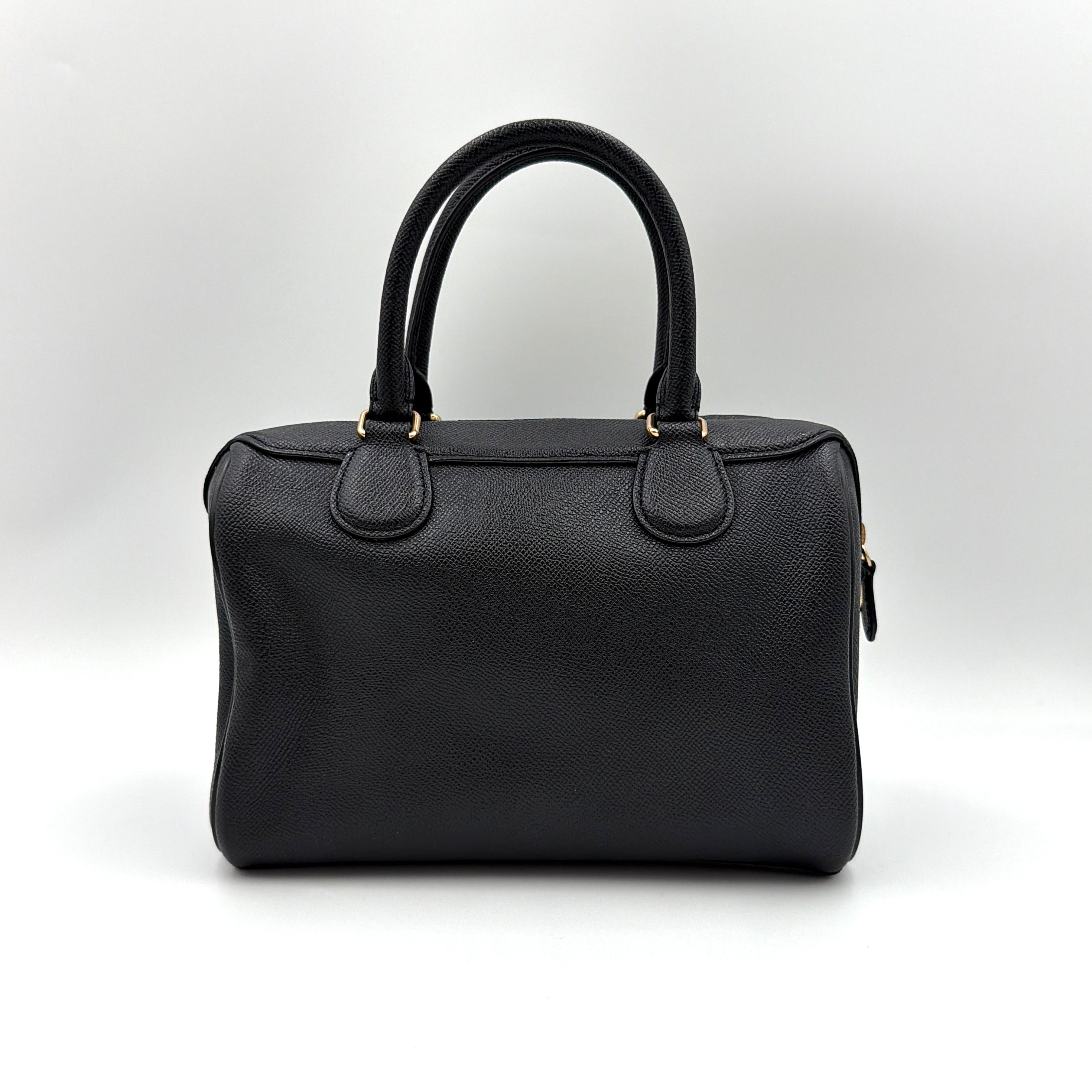 Coach Mini Bennett Boston Bag in black pebbled leather with gold hardware and detachable strap, styled against a clean backdrop.