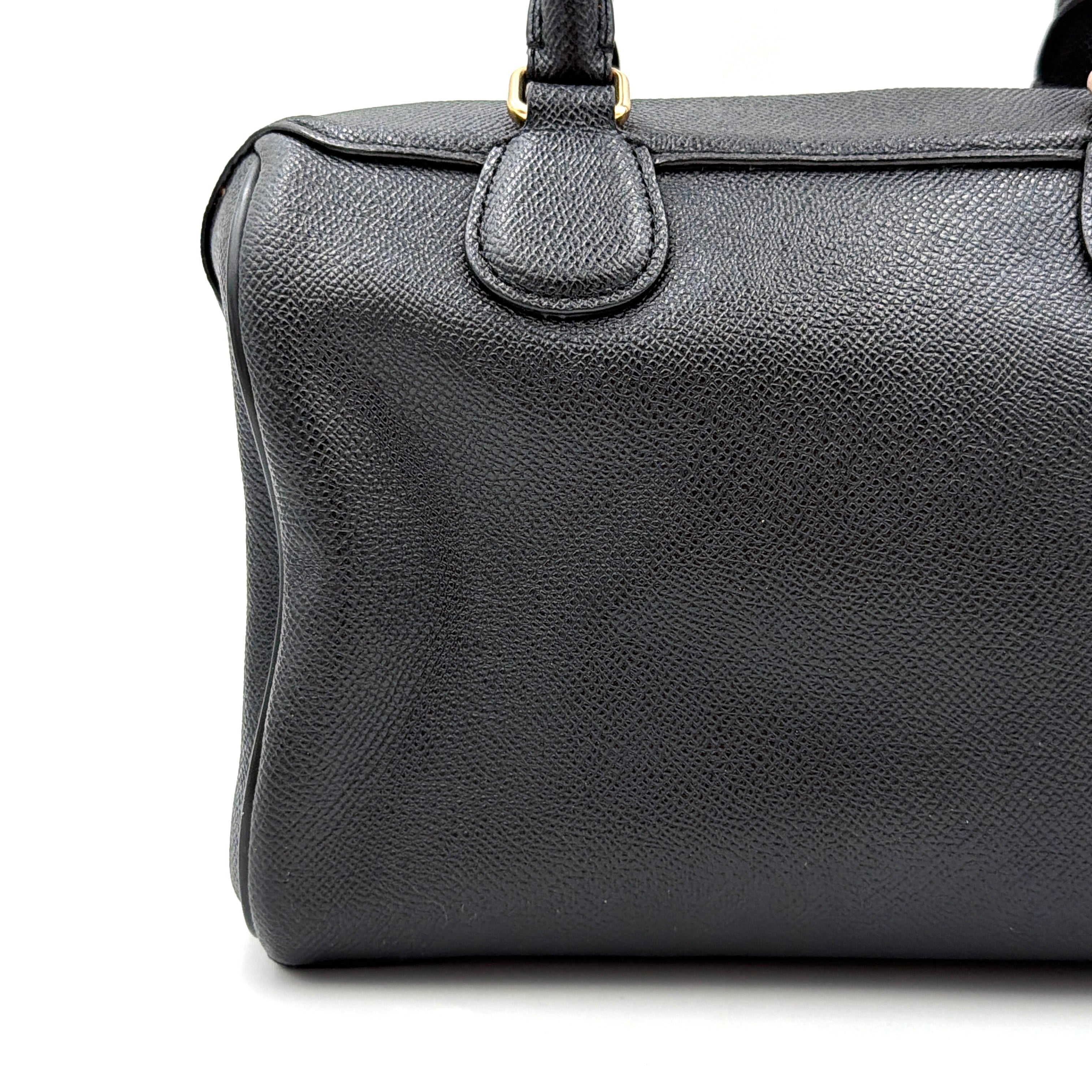 Coach Mini Bennett Boston Bag in black pebbled leather with gold hardware and detachable strap, styled against a clean backdrop.