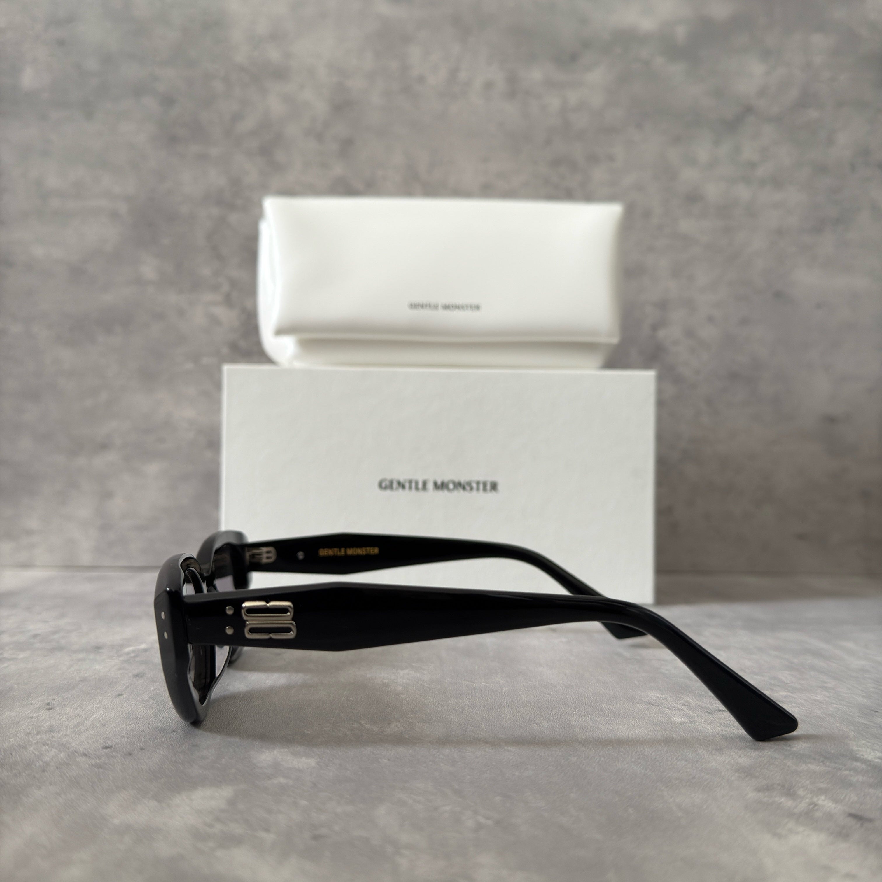 Gentle Monster ROCOCO - 01 black tinted sunglasses with a sleek acetate frame and gold-tone logo on temples.