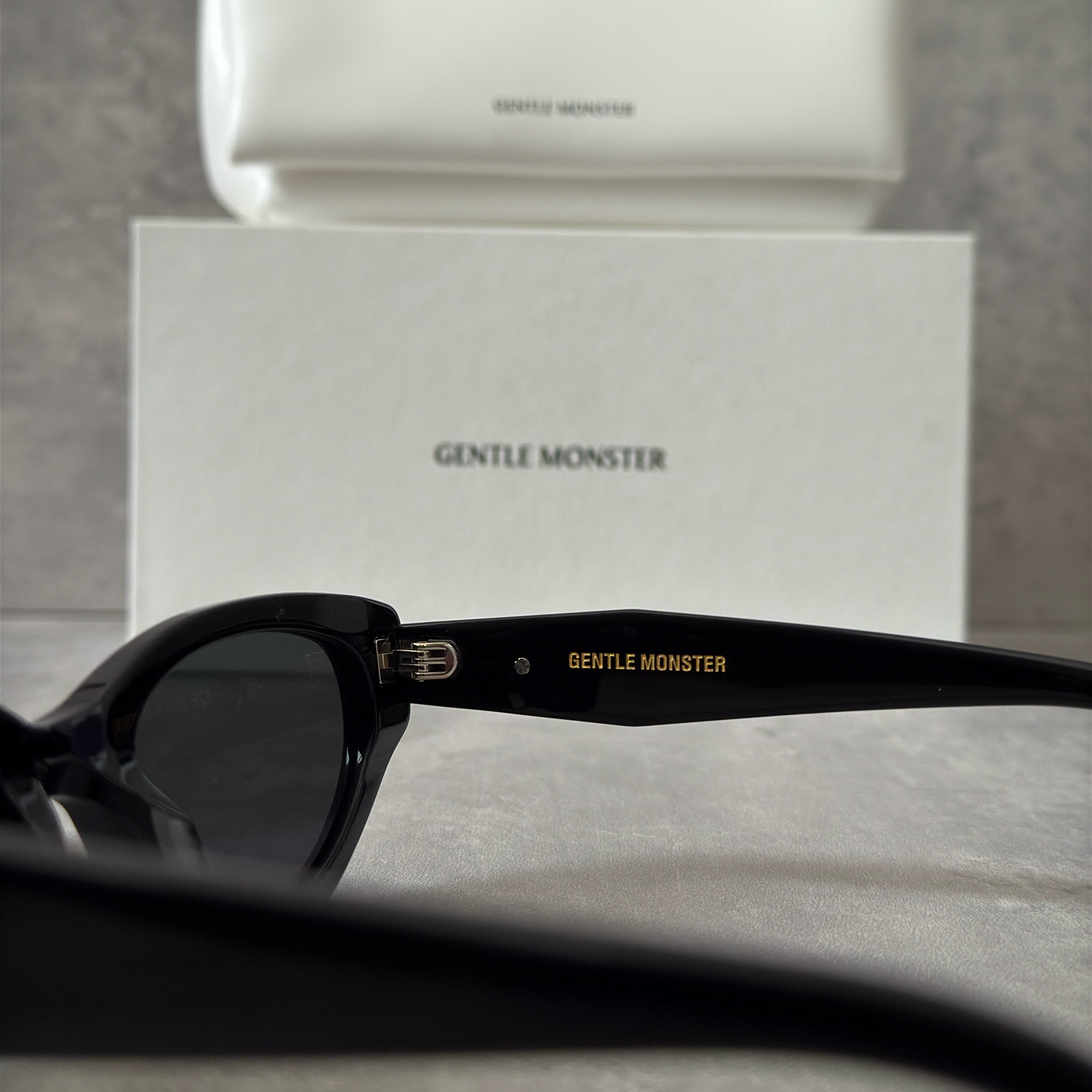 Gentle Monster ROCOCO - 01 black tinted sunglasses with a sleek acetate frame and gold-tone logo on temples.