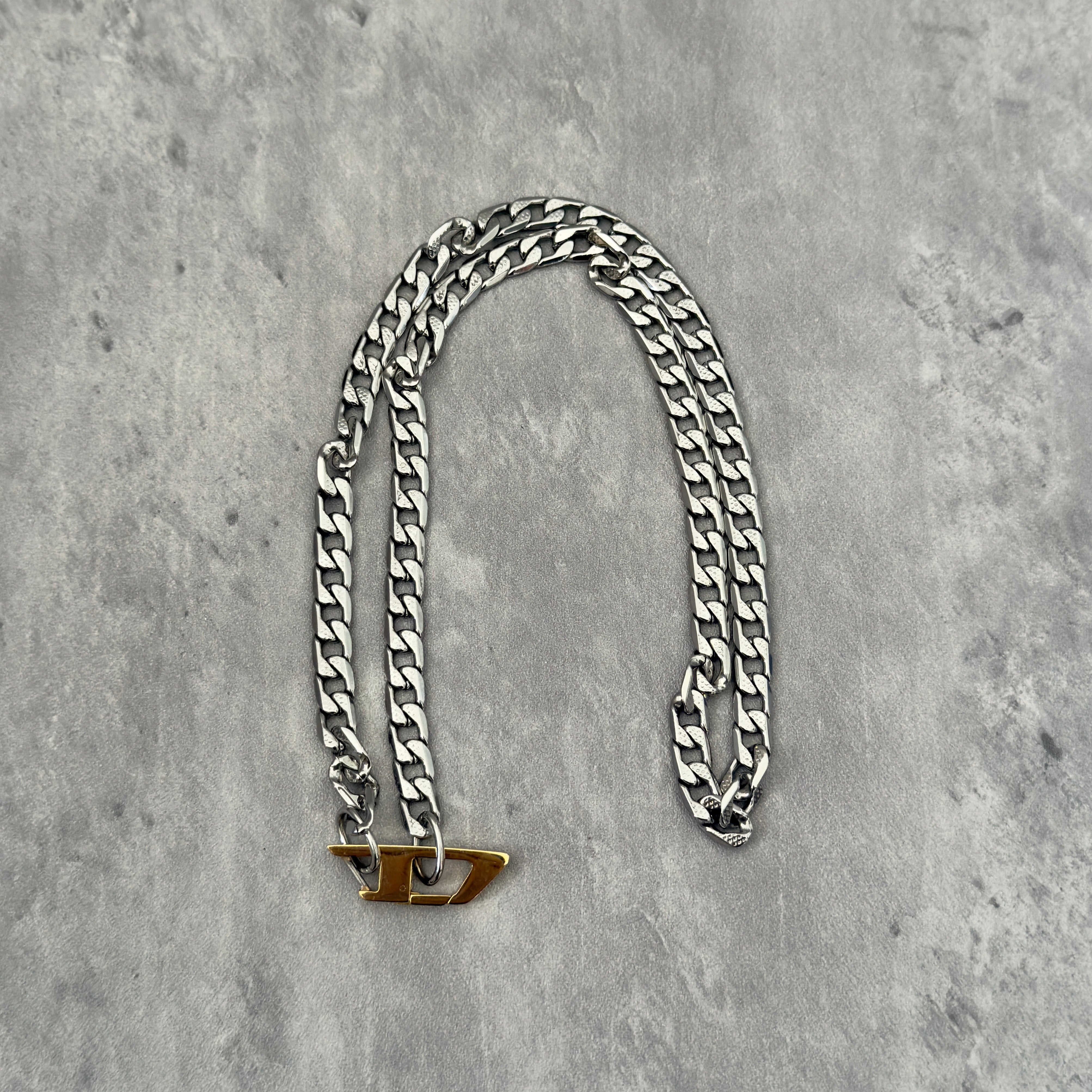 Diesel Signature Gold D-Logo Stainless Steel Necklace, featuring a silver-tone chunky chain with a gold-tone Diesel "D" logo pendant.