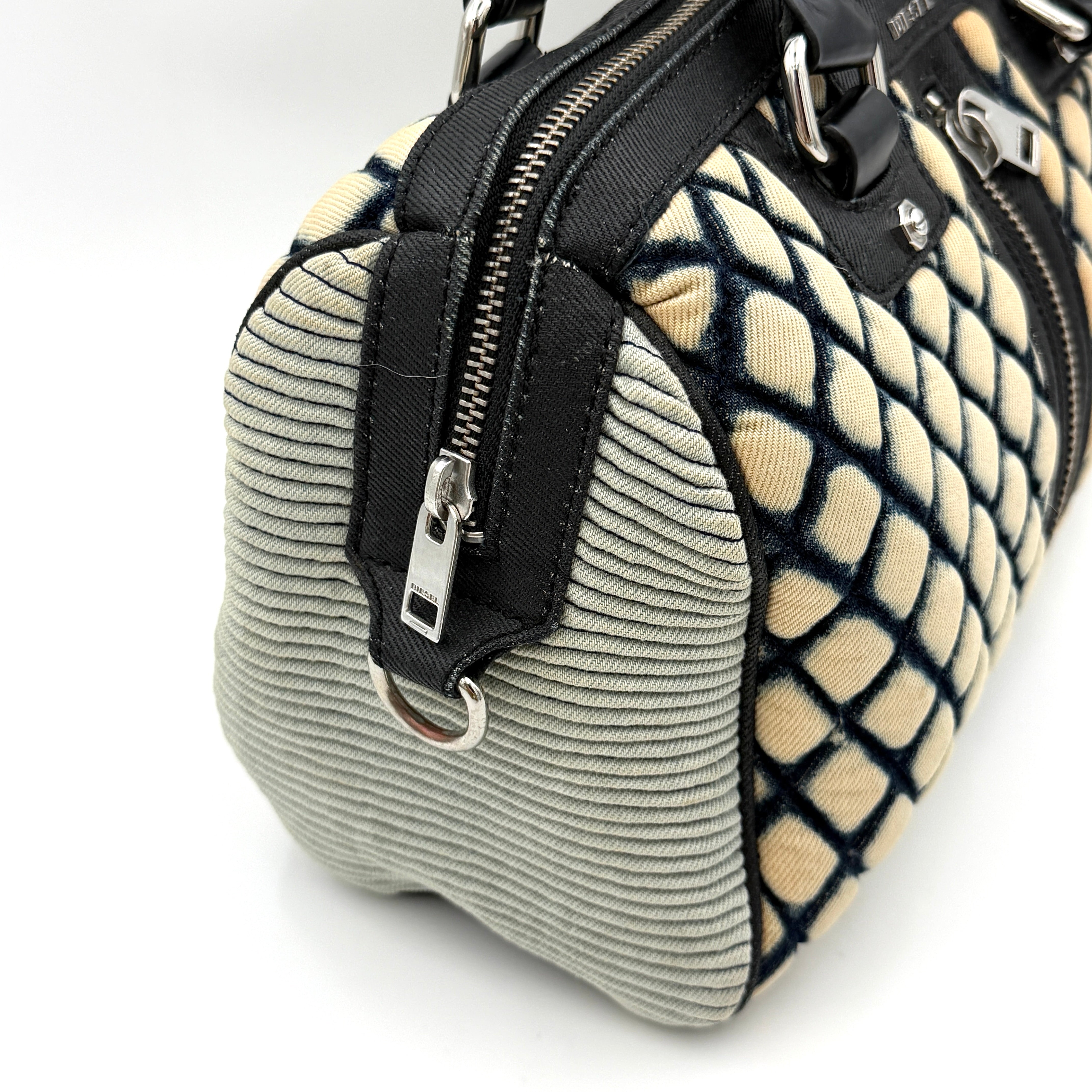 Diesel 2Way Boston Handbag in cream canvas with black velvet-effect lattice, dual leather handles, and detachable strap displayed in front.