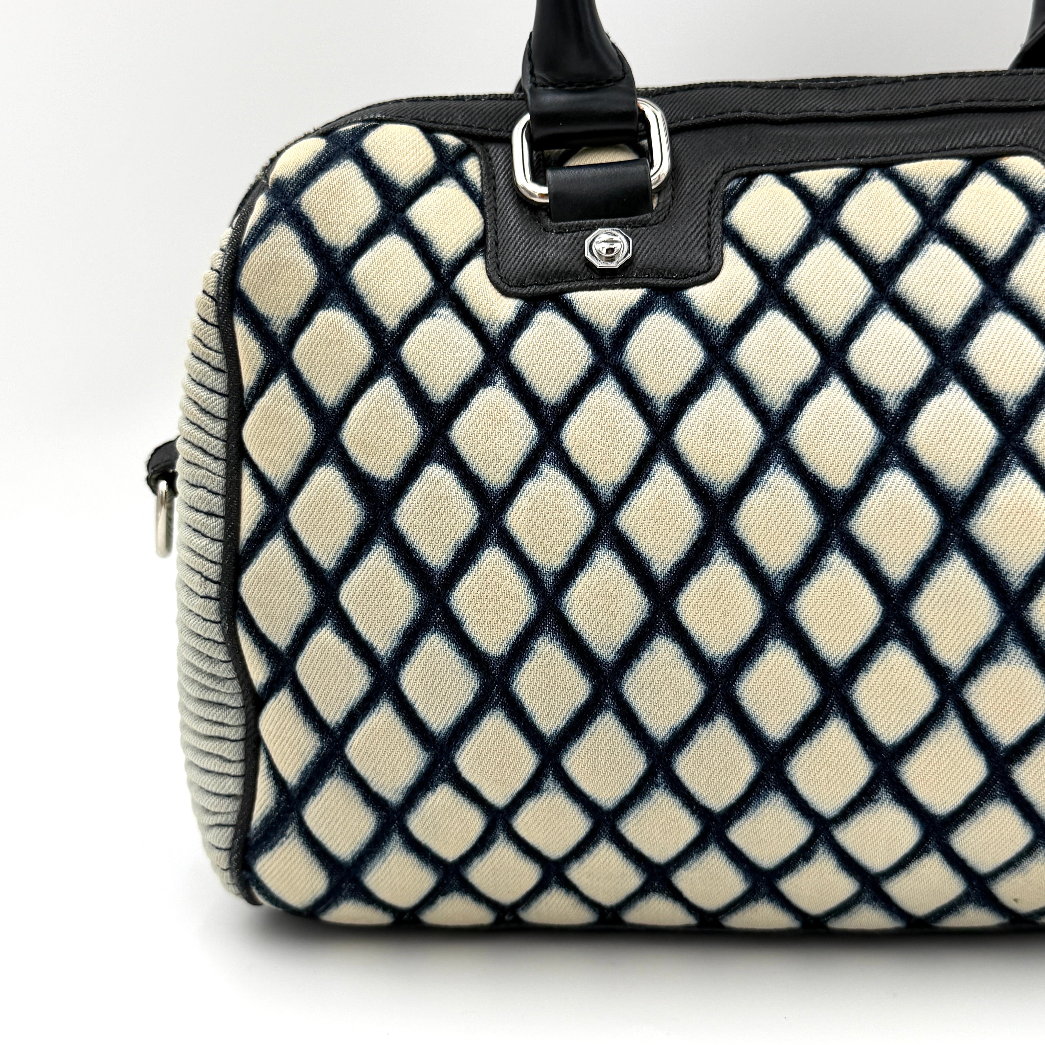 Diesel 2Way Boston Handbag in cream canvas with black velvet-effect lattice, dual leather handles, and detachable strap displayed in front.