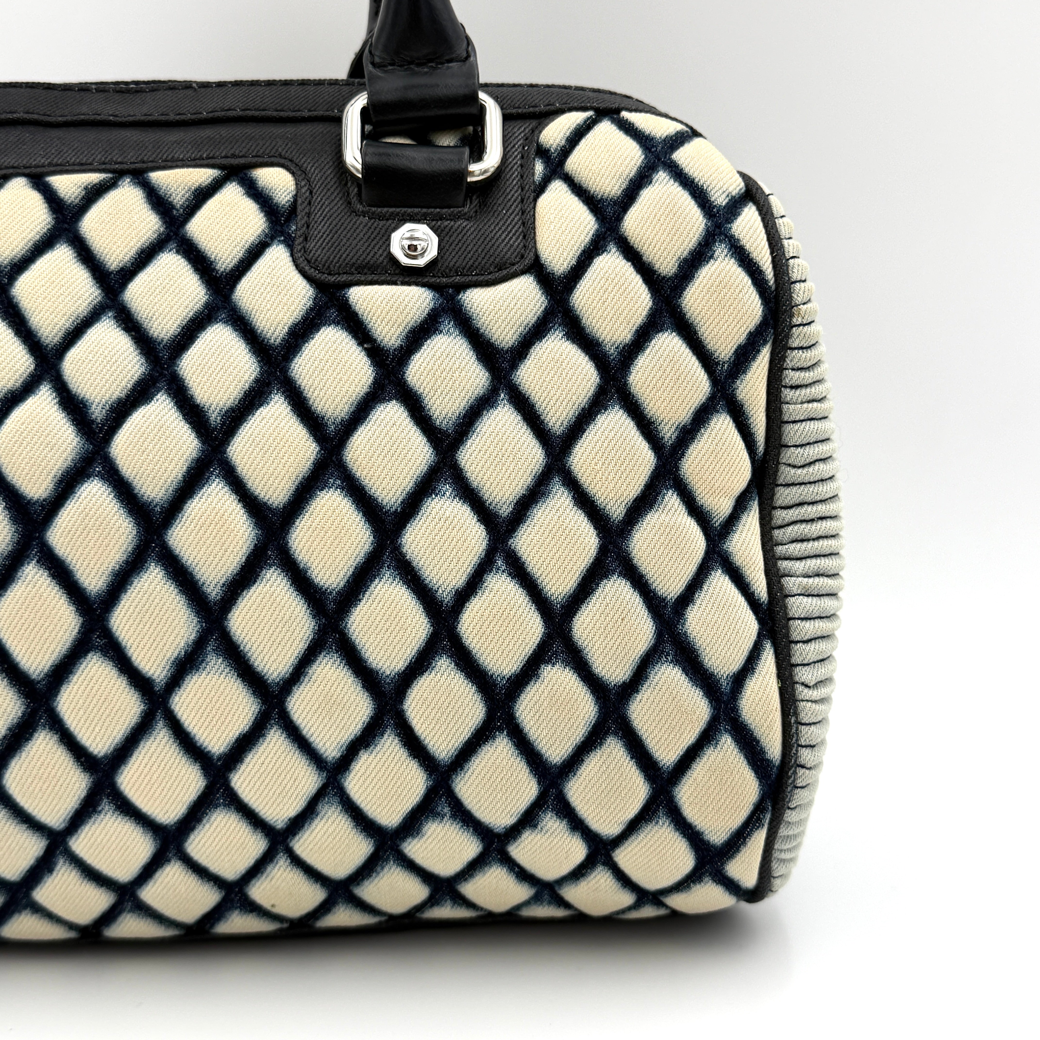 Diesel 2Way Boston Handbag in cream canvas with black velvet-effect lattice, dual leather handles, and detachable strap displayed in front.