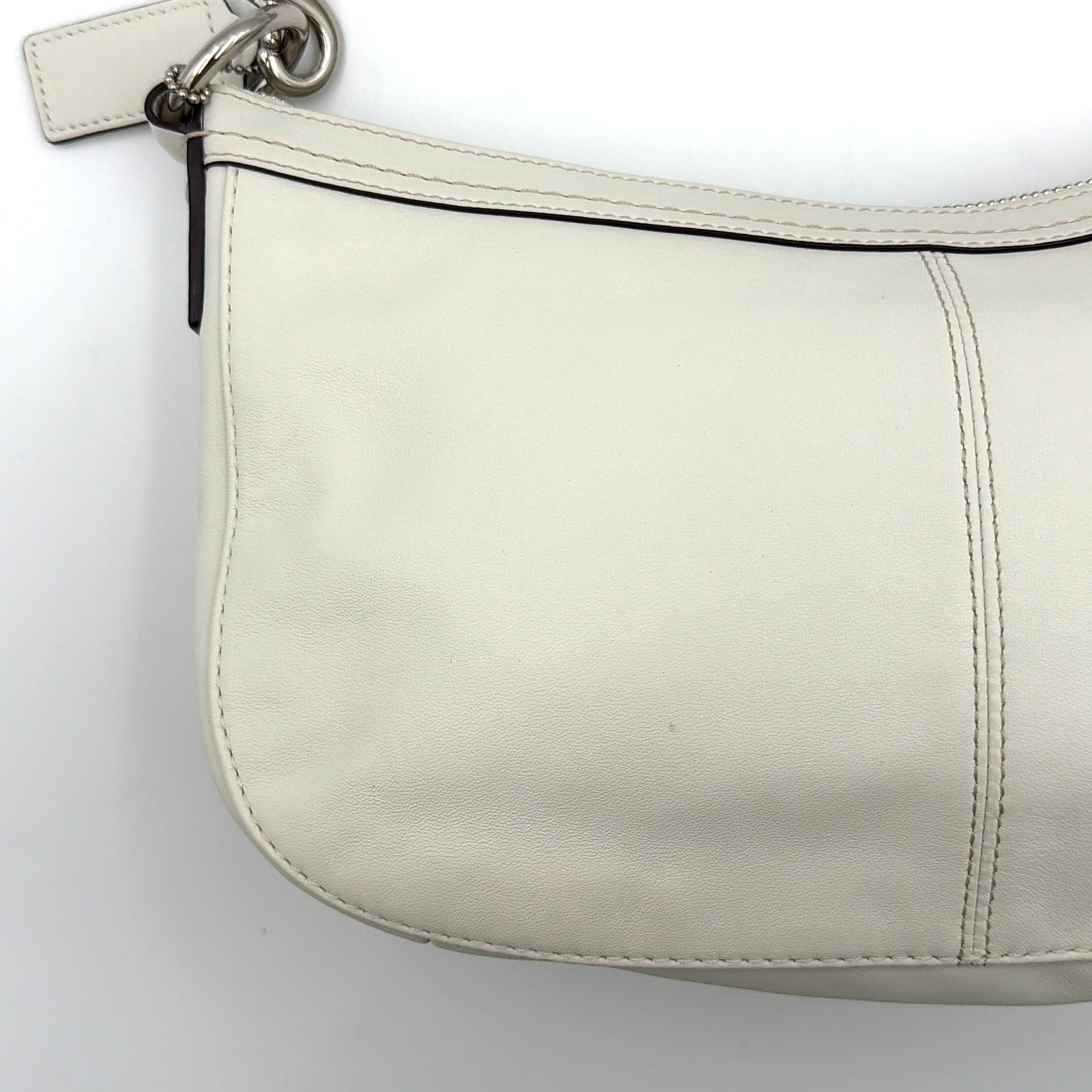 Coach 2Way Buckle Shoulder Bag in smooth ivory leather with silver-tone hardware and an adjustable strap, styled against a white background.