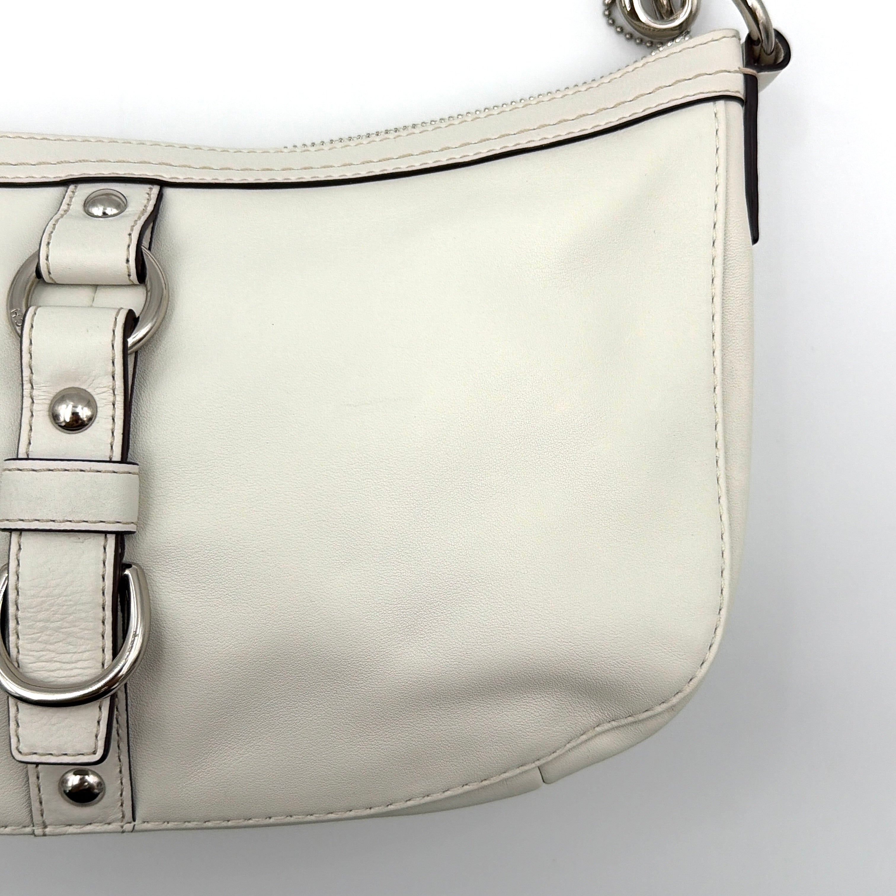 Coach 2Way Buckle Shoulder Bag in smooth ivory leather with silver-tone hardware and an adjustable strap, styled against a white background.