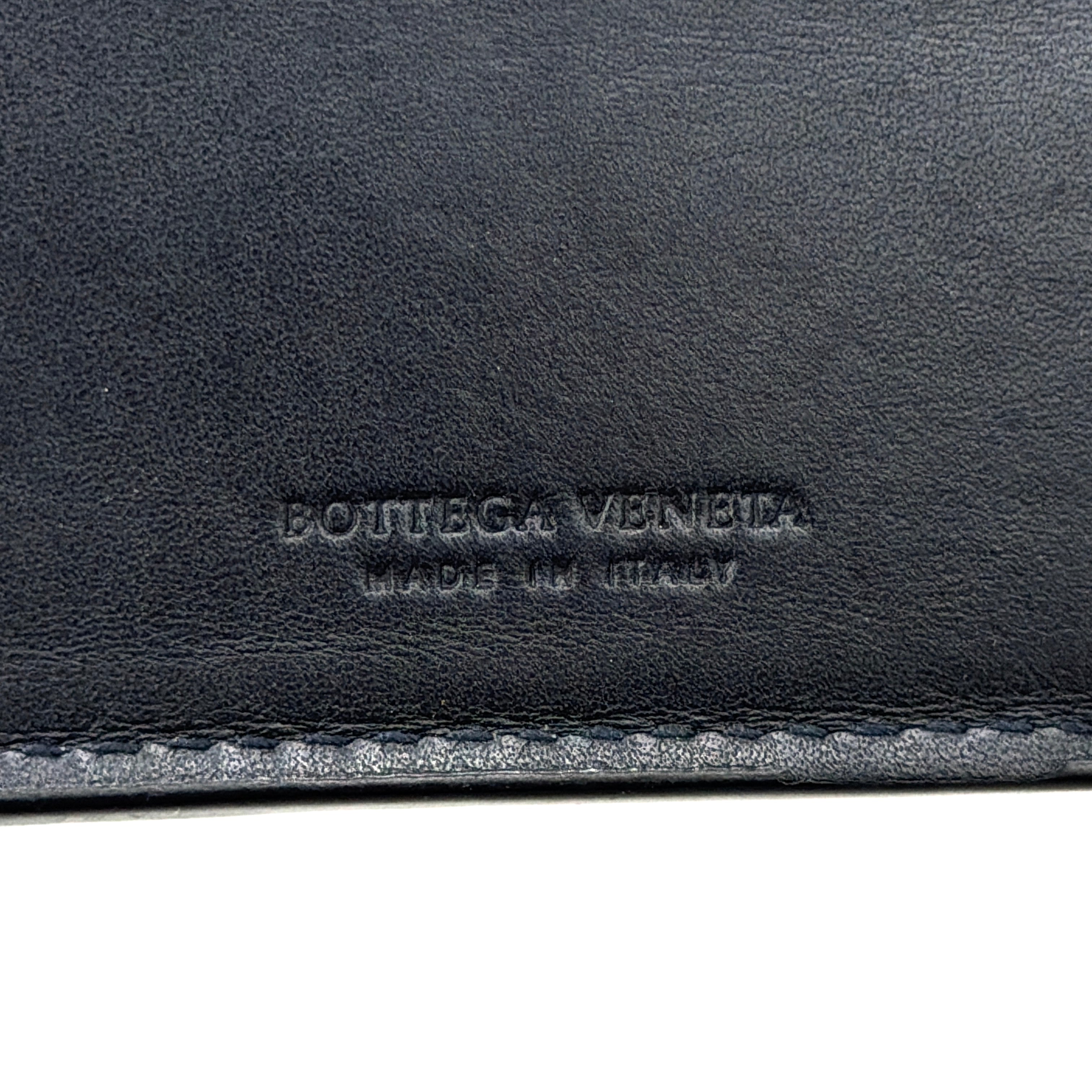 Black Bottega Veneta Intrecciato leather wallet with signature woven pattern photographed against a clean background.