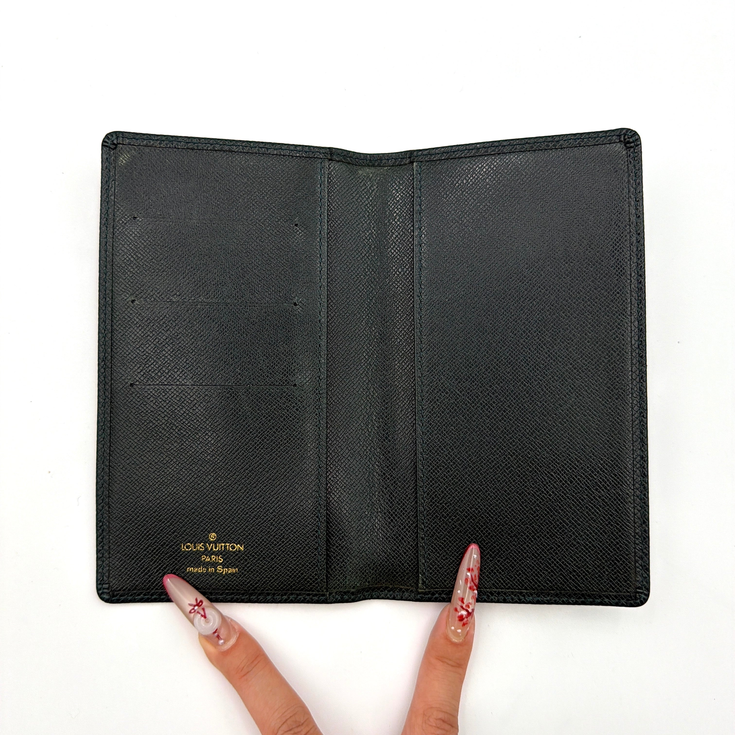 A Louis Vuitton Taiga Brazza Wallet in dark green, showcasing fine cross-grain leather texture and the understated LV monogram debossed on the front.