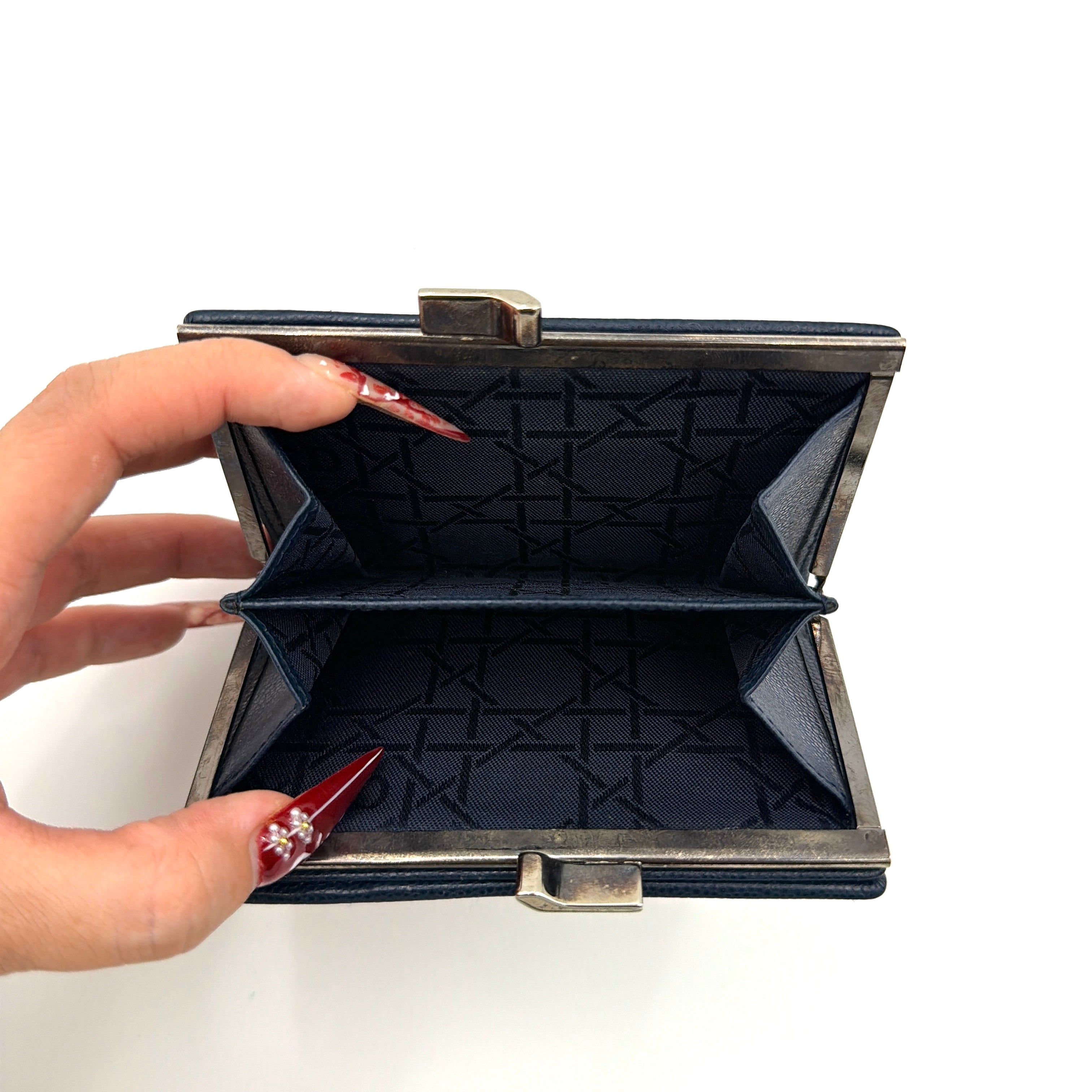 Dior compact navy blue leather wallet with silver-tone logo plaque and kiss-lock clasp, showcased against a clean background.