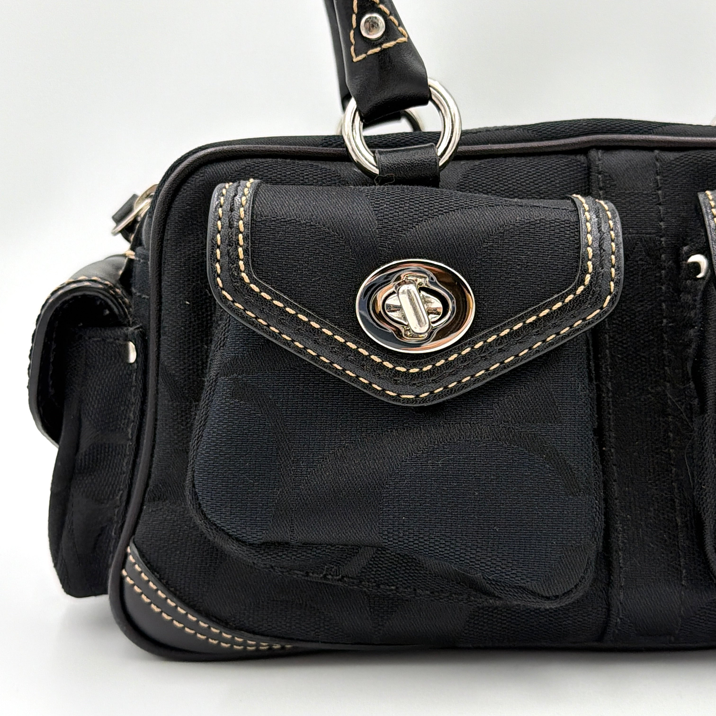 Coach black Signature Gallery satchel with double handles and silver hardware, set against a clean background.