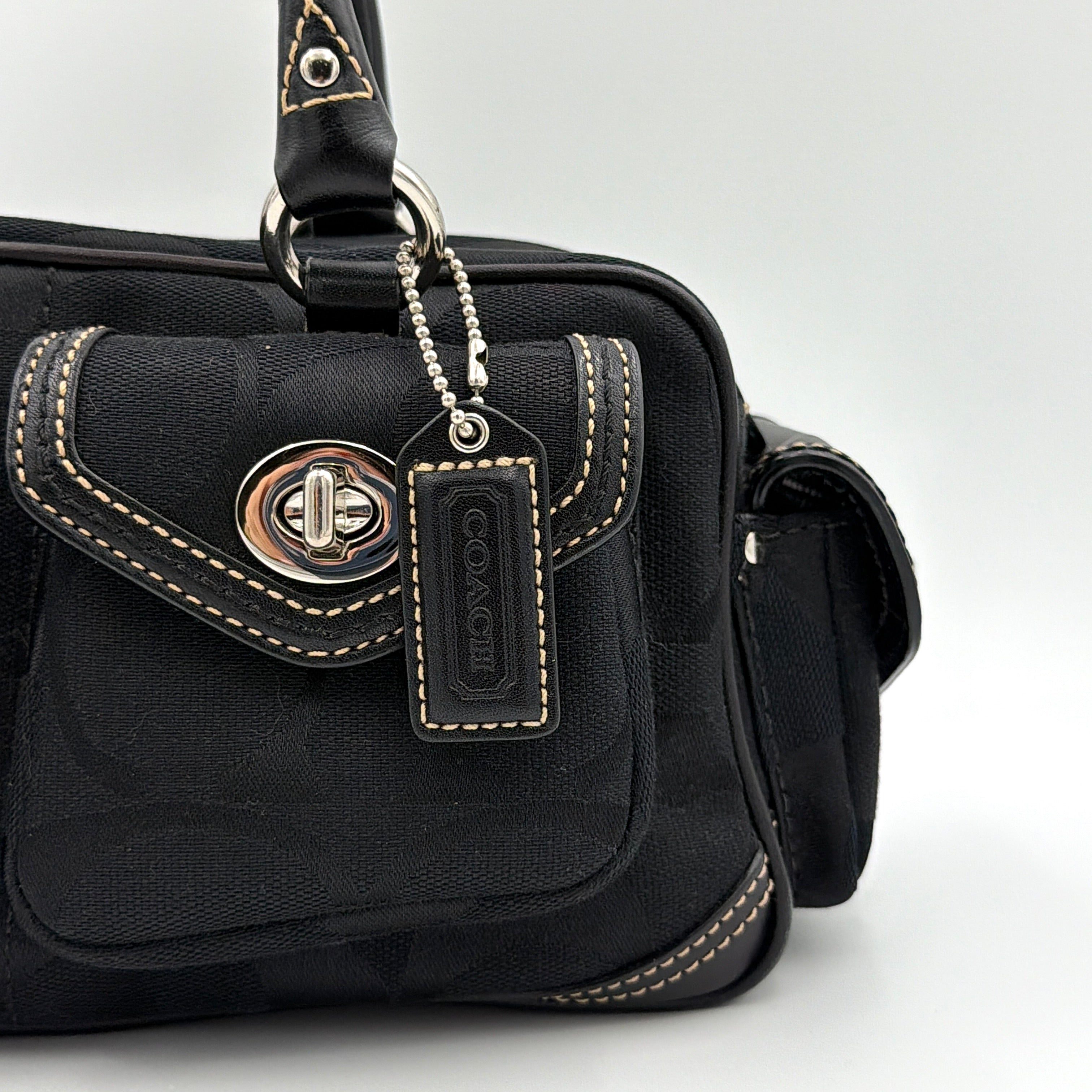 Coach black Signature Gallery satchel with double handles and silver hardware, set against a clean background.